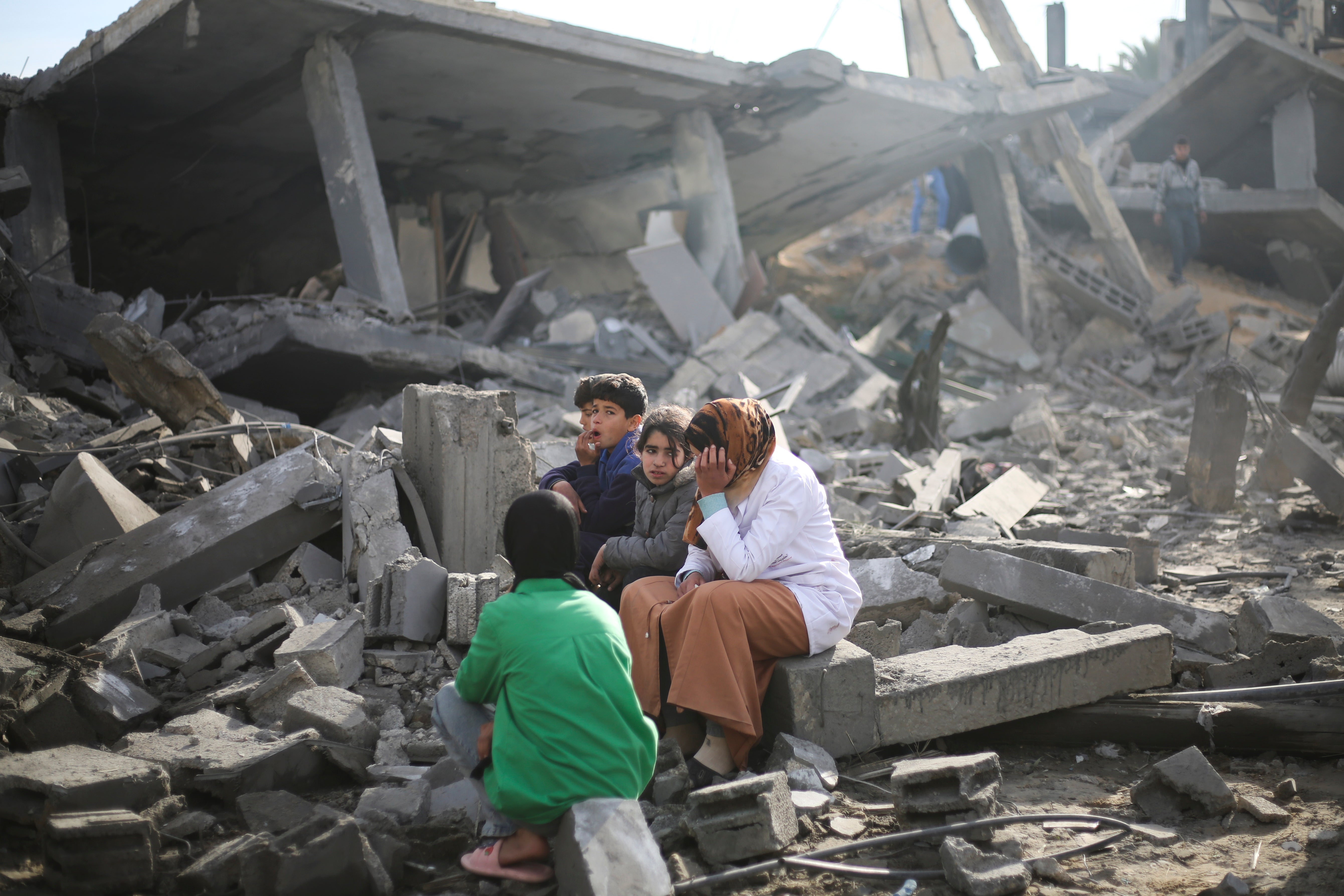 Palestinians sit by the destruction from the Israeli bombardment of the Gaza Strip in Rafah