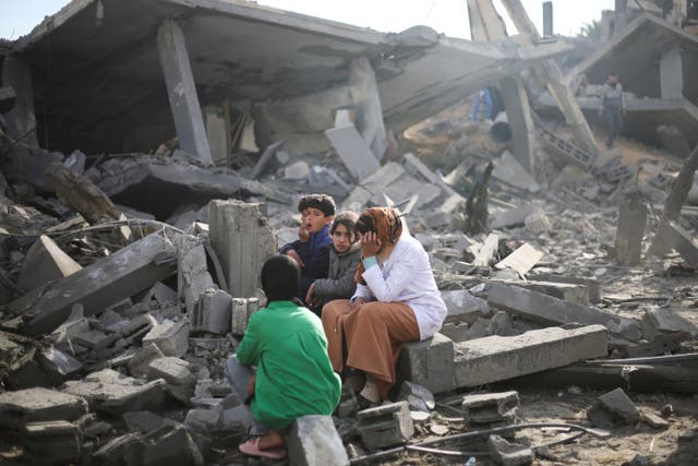 <p>Palestinians sit by the destruction from the Israeli bombardment in Rafah </p>