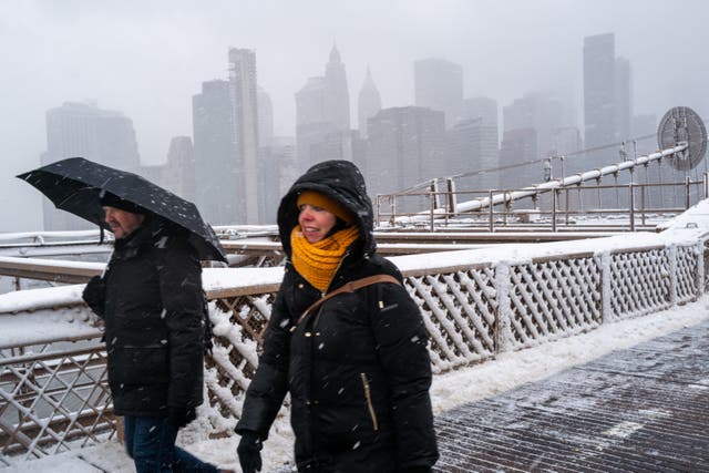 <p>People walk across the Brooklyn Bridge in the blowing snow in Manhattan </p>