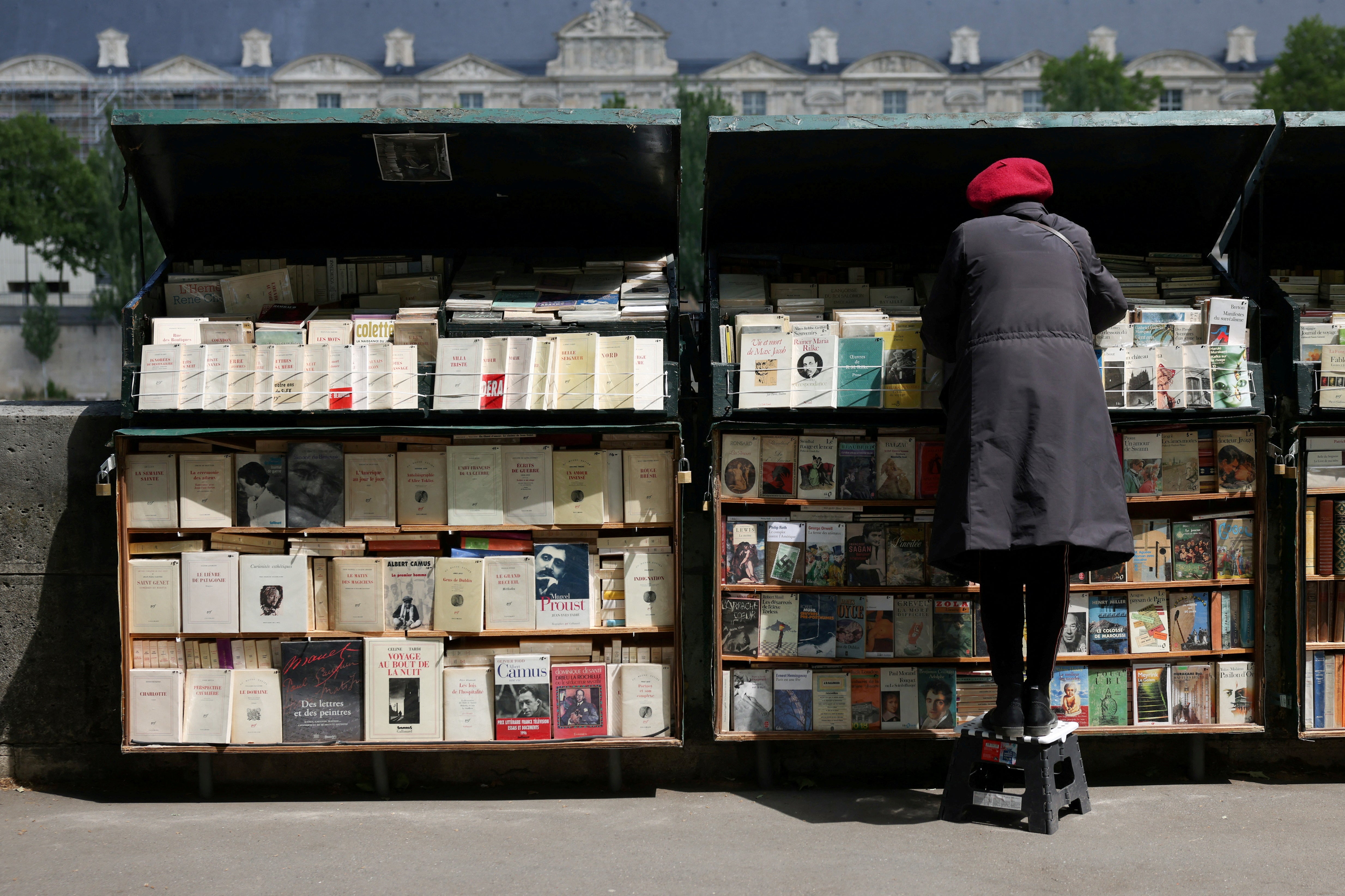 A book seller prepares her stall along the edge of The Seine in Paris