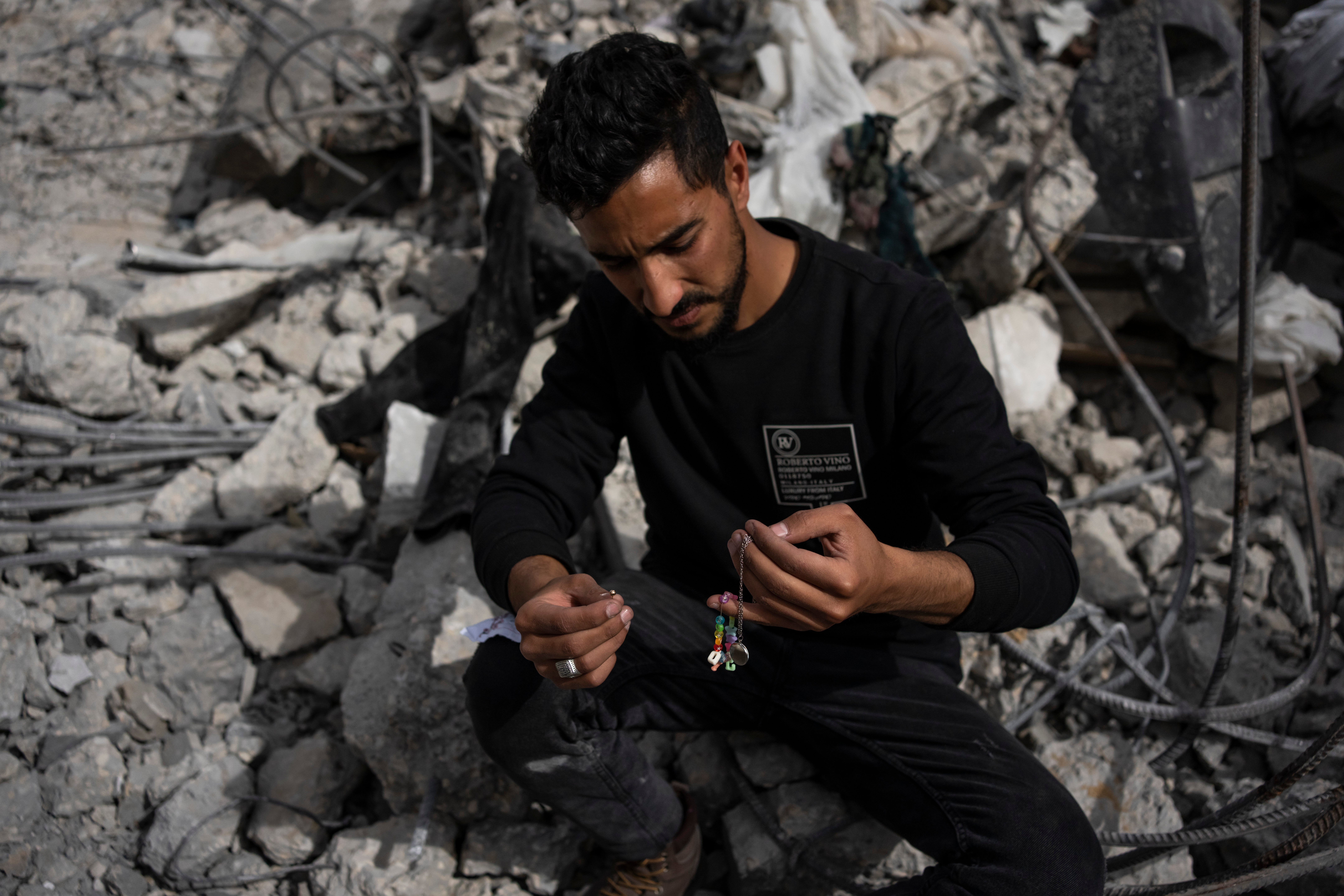 Ibrahim Hasouna, center, the sole survivor among his family, sits amidst the debris of his bombed home in Rafa