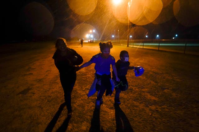 <p>In this May 2021 photo, three young migrants hold hands as they run in the rain at an intake area after turning themselves in upon crossing the U.S.-Mexico border in Roma, Texas</p>
