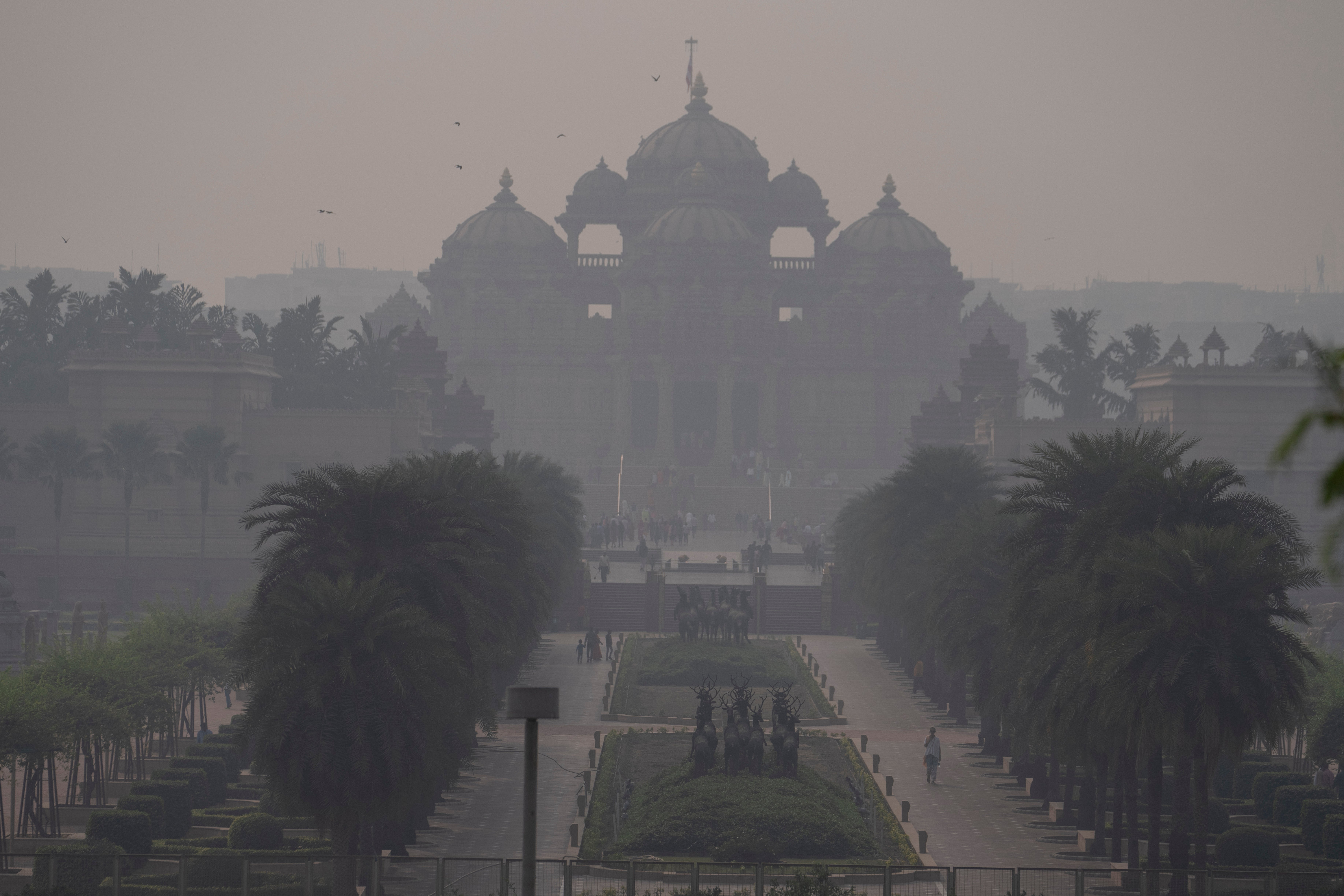 People visiting the Akshardham temple are visible through a thick smog in New Delhi, India, Wednesday, 8 Nov 2023