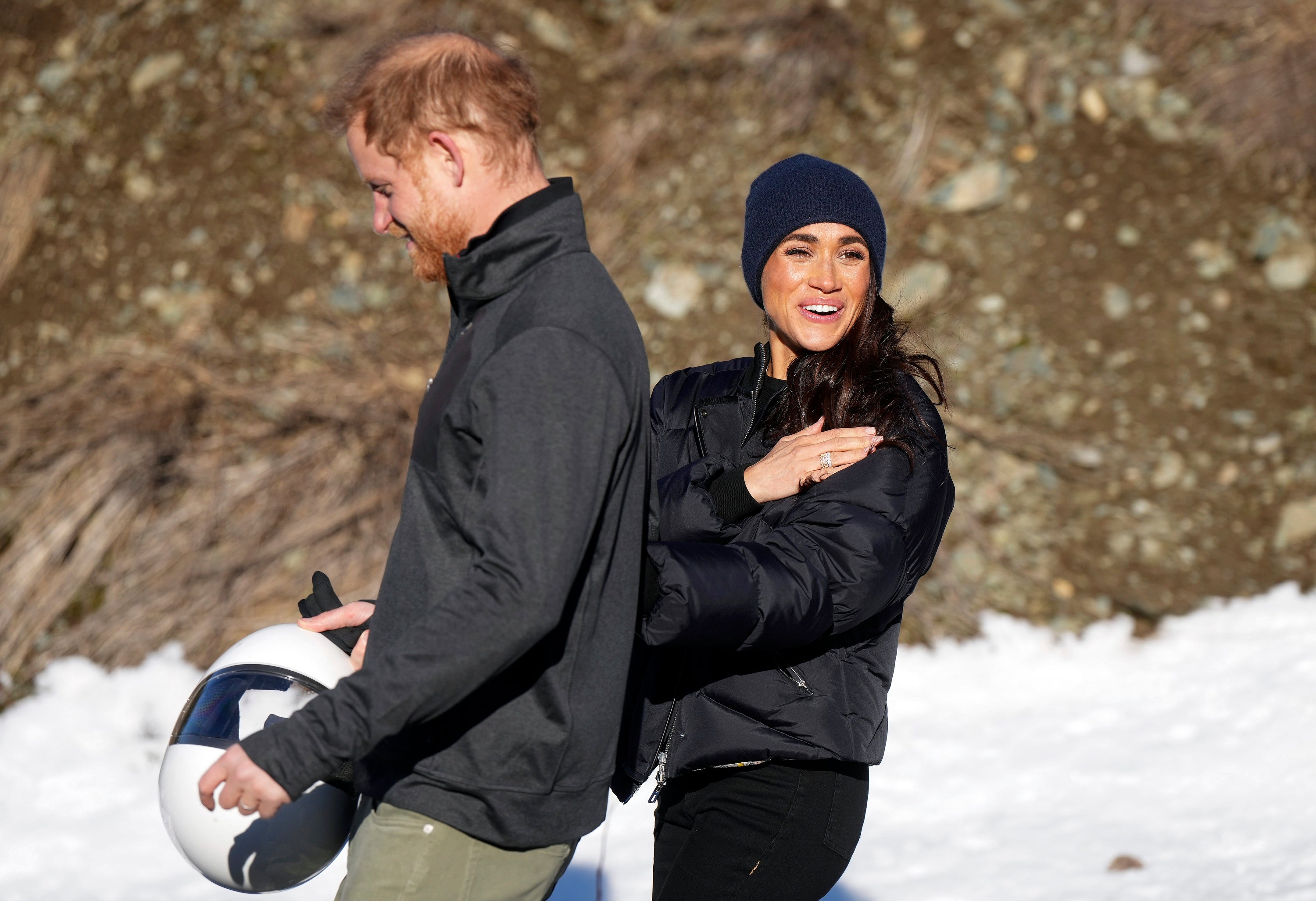 Prince Harry and Meghan, the Duke and Duchess of Sussex, walk together after Harry slid down the track