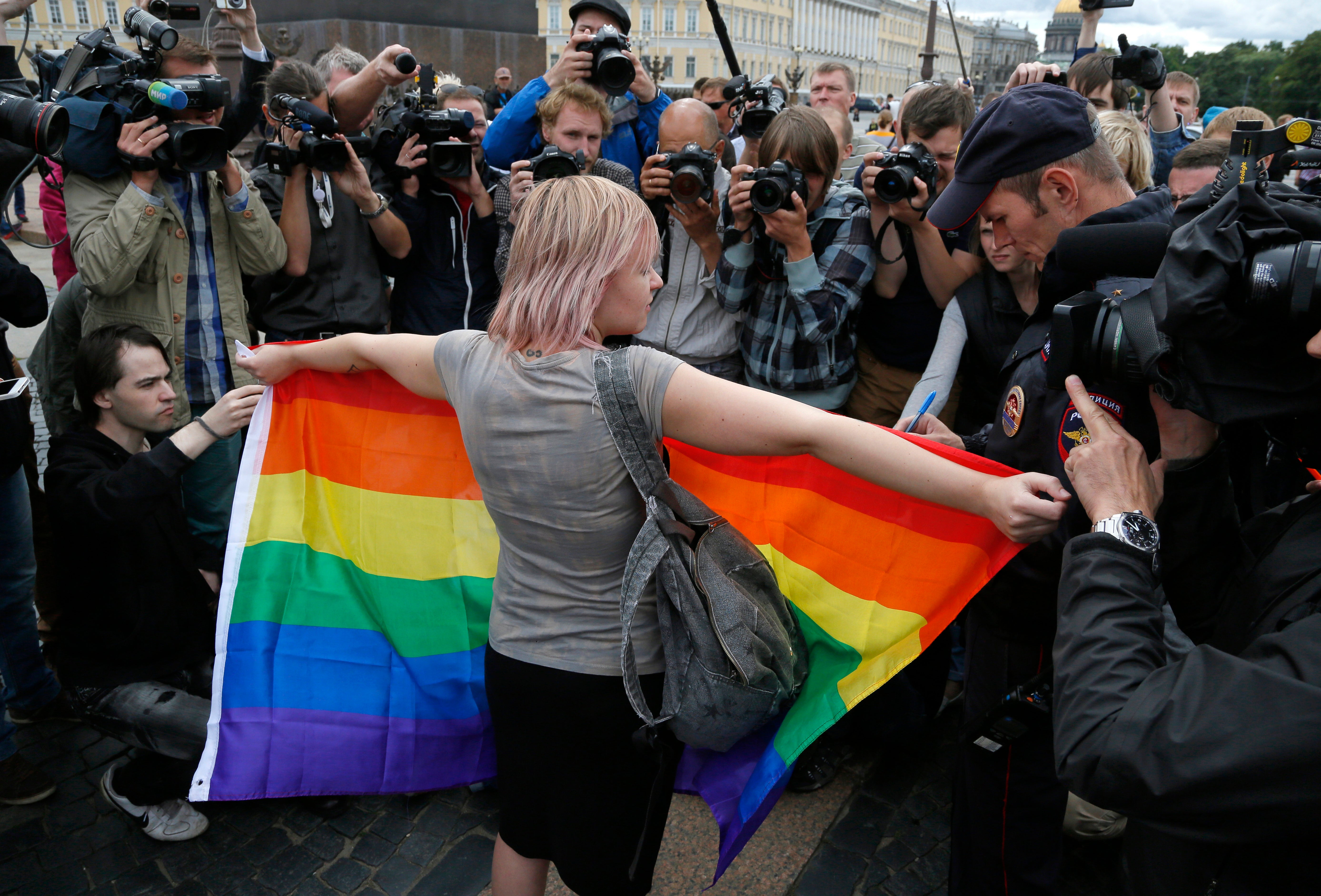 A gay rights activist stands with a rainbow flag, in front of journalists, during a protest in Russia
