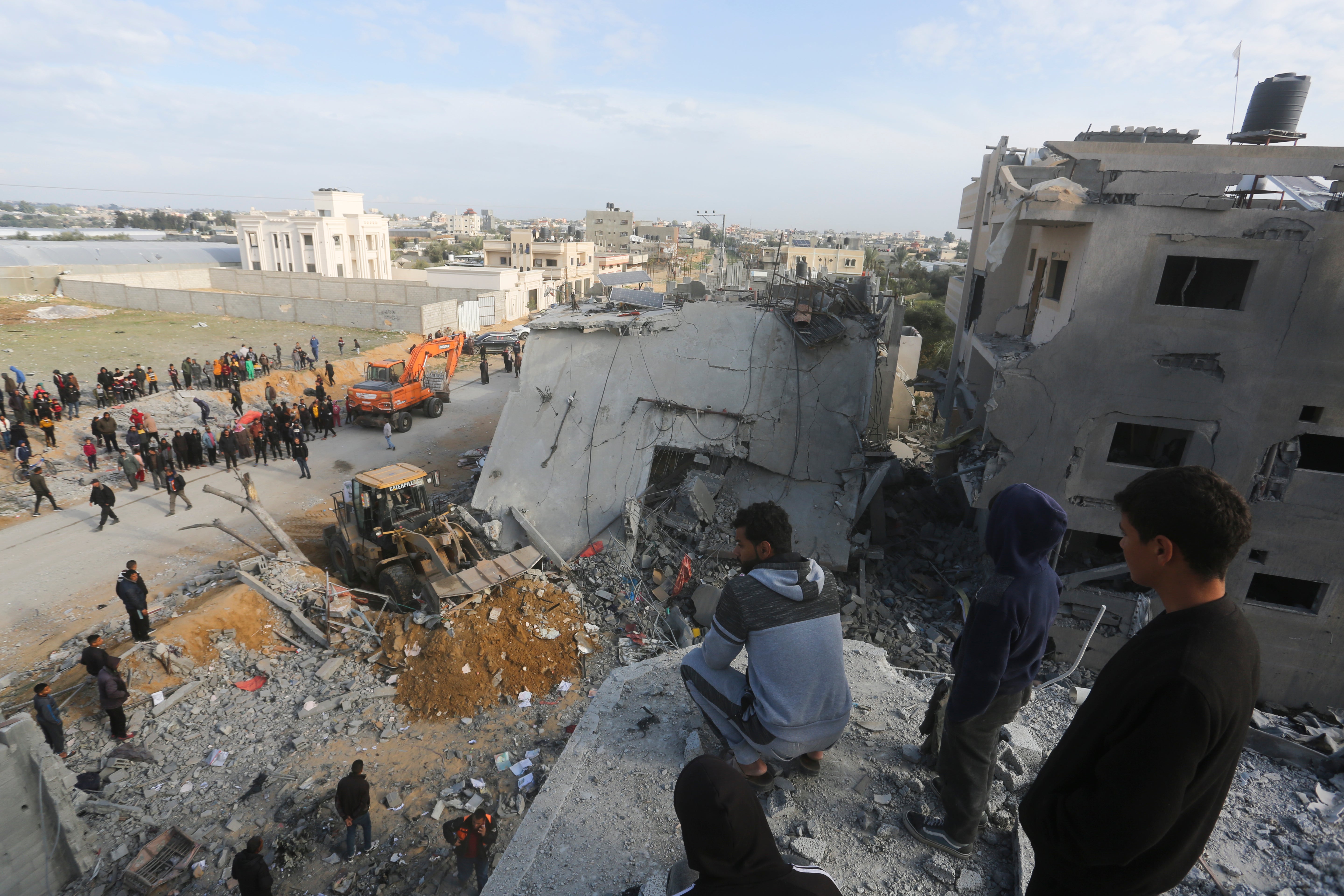 Palestinians look at the destruction after an Israeli strike on a residential building in Rafah, in the Gaza Strip