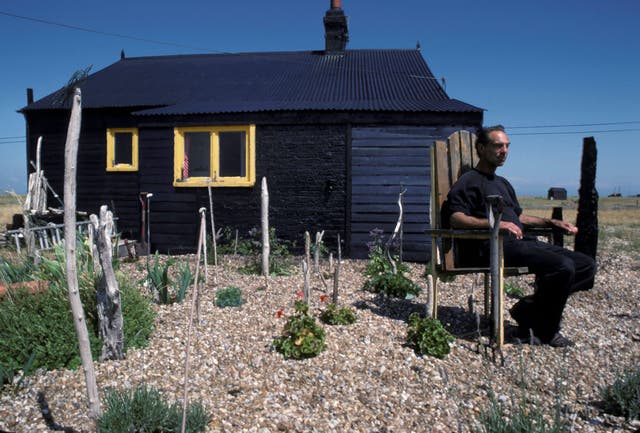 <p>Derek Jarman in his shingle garden at Prospect Cottage, Dungeness</p>