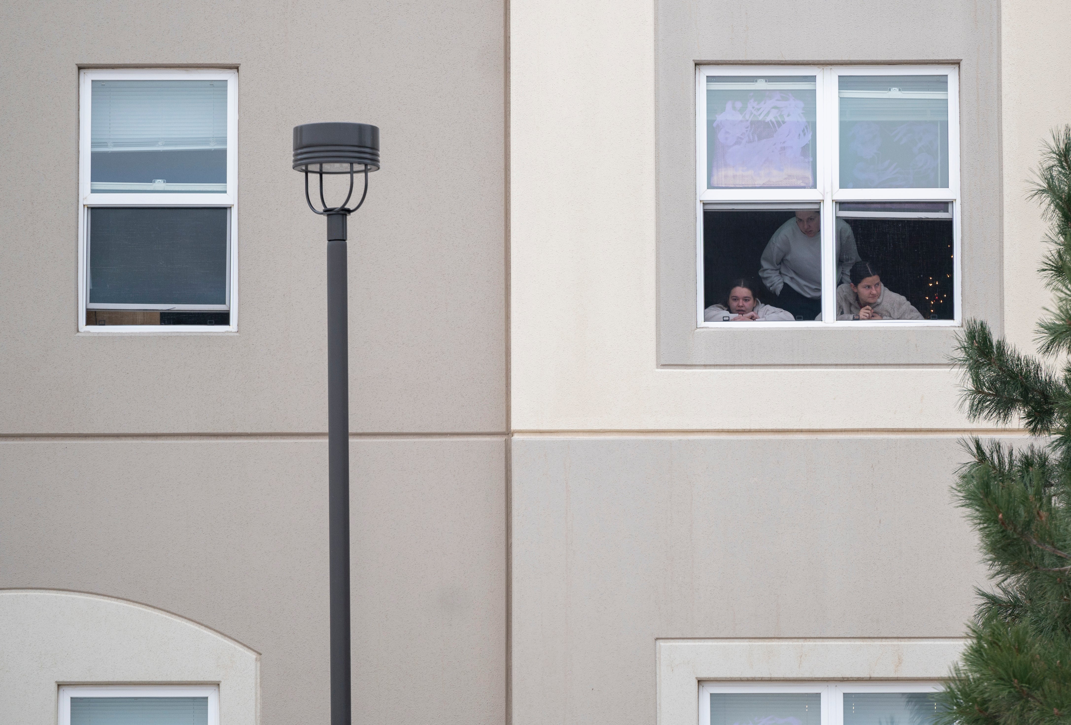Students look outside their dorm window in the Village at Alpine Valley housing, as police investigate a shooting on the University of Colorado Colorado Springs campus