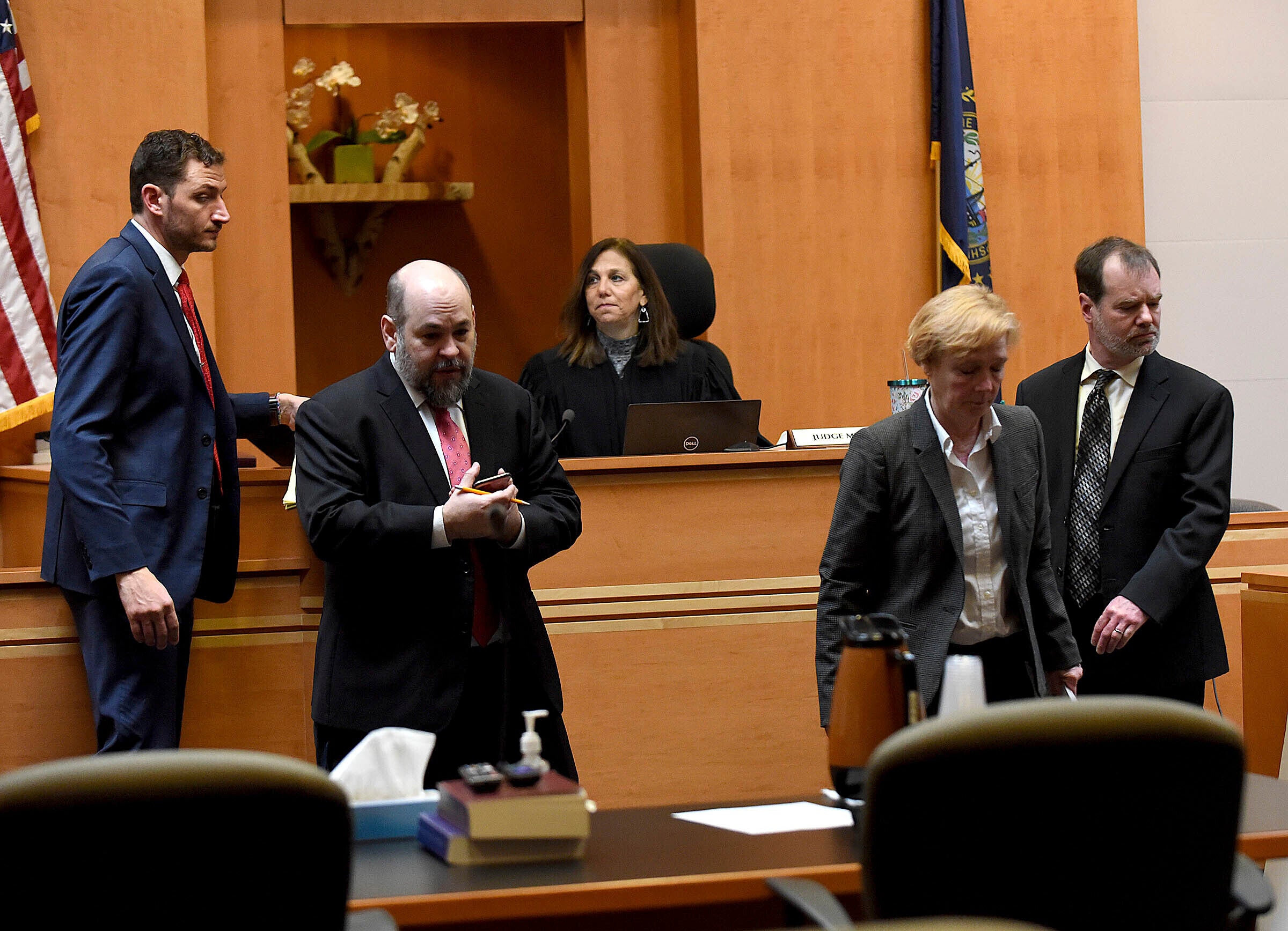 Superior Court Justice Amy Messer, background, watches as Assistant New Hampshire Attorney General Christopher Knowles, from left, Senior Assistant New Hampshire Attorney General Benjamin Agati and defence lawyers Caroline Smith and James Brooks walks back to their posts following a bench meeting