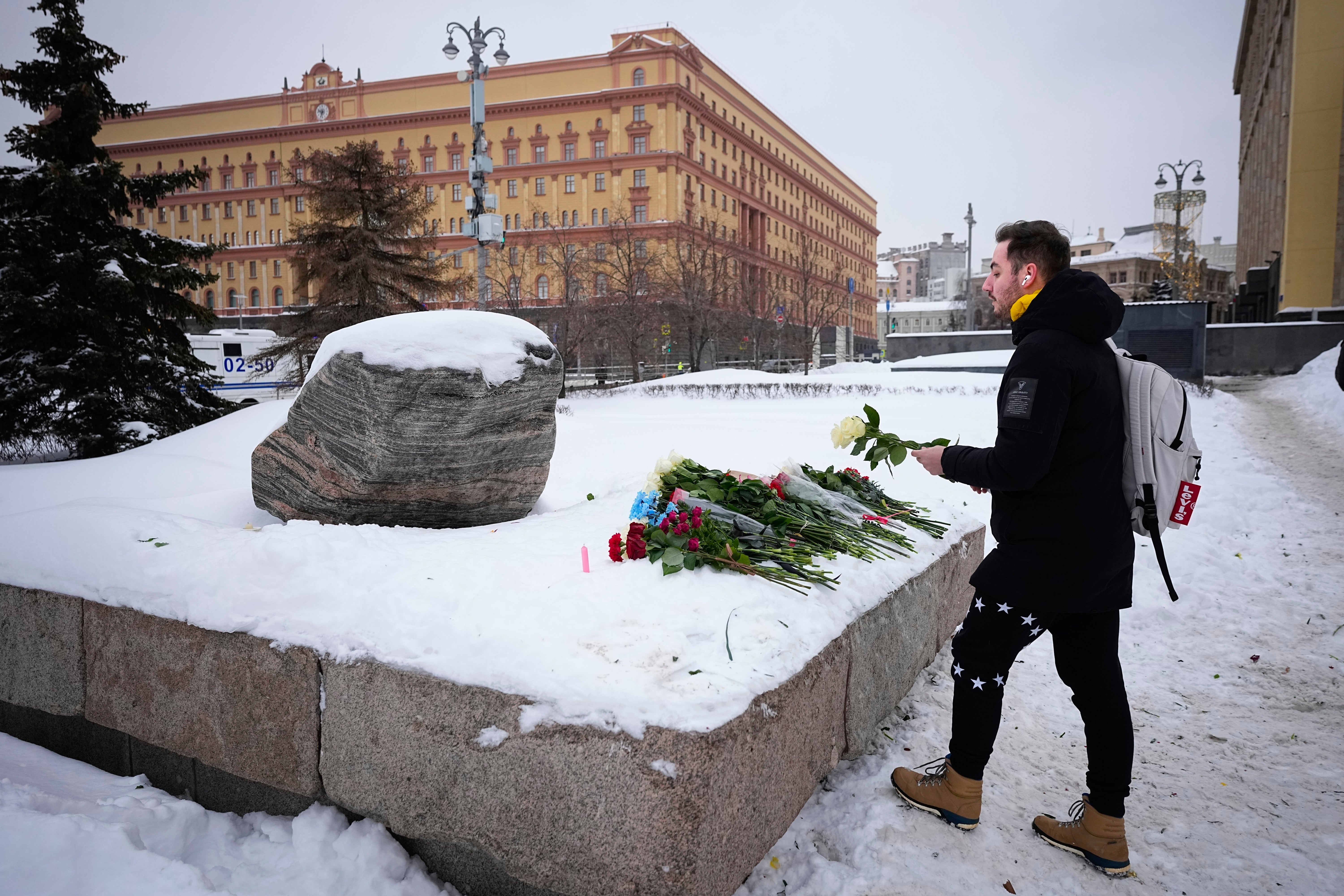 A man lays flowers paying the last respect to Alexei Navalny at the monument, a large boulder from the Solovetsky island
