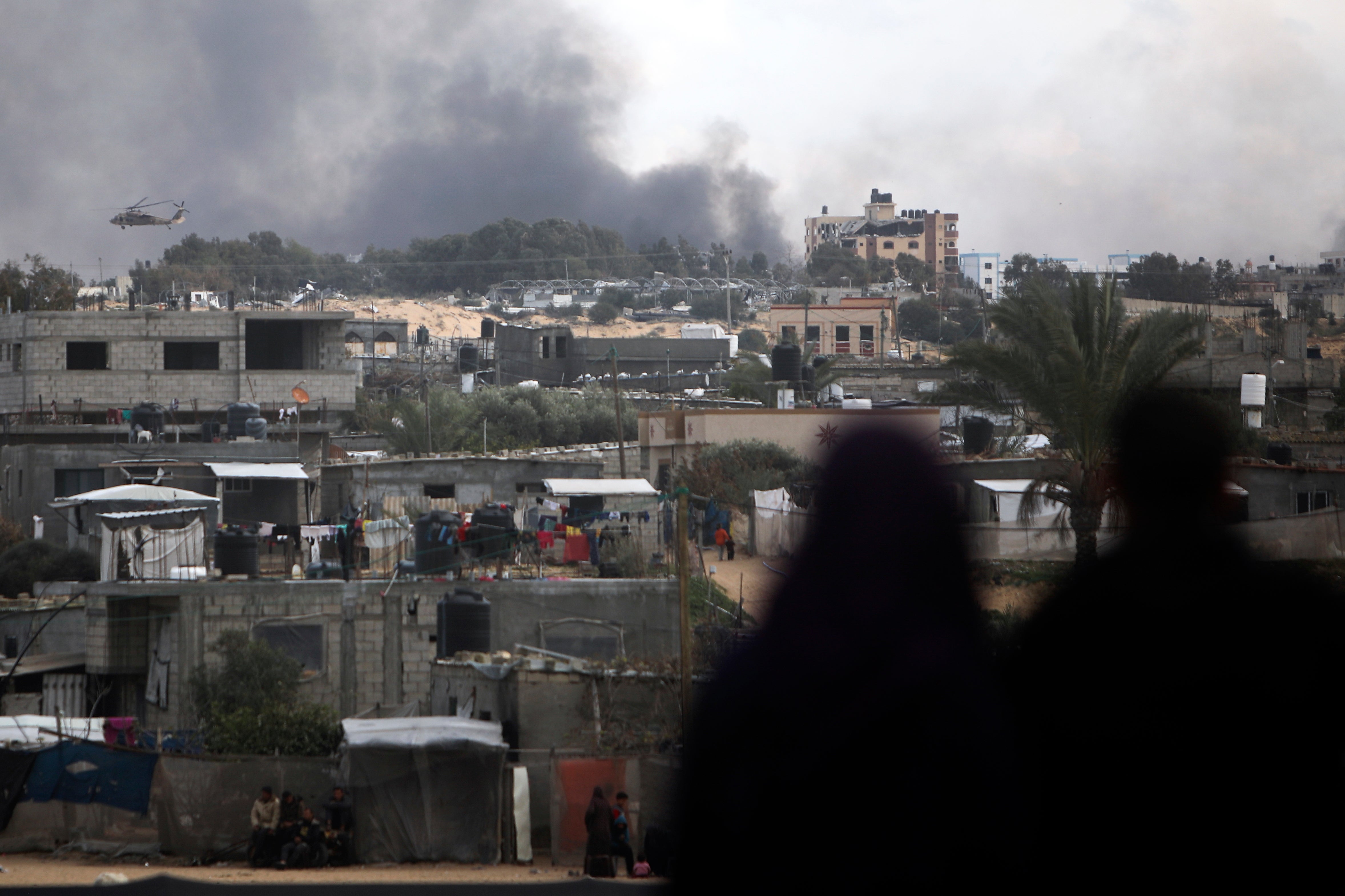 Palestinians watch an Israeli helicopter fly over Khan Younis in the Gaza Strip