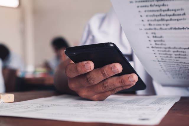 <p>A student using their mobile phone during an exam </p>