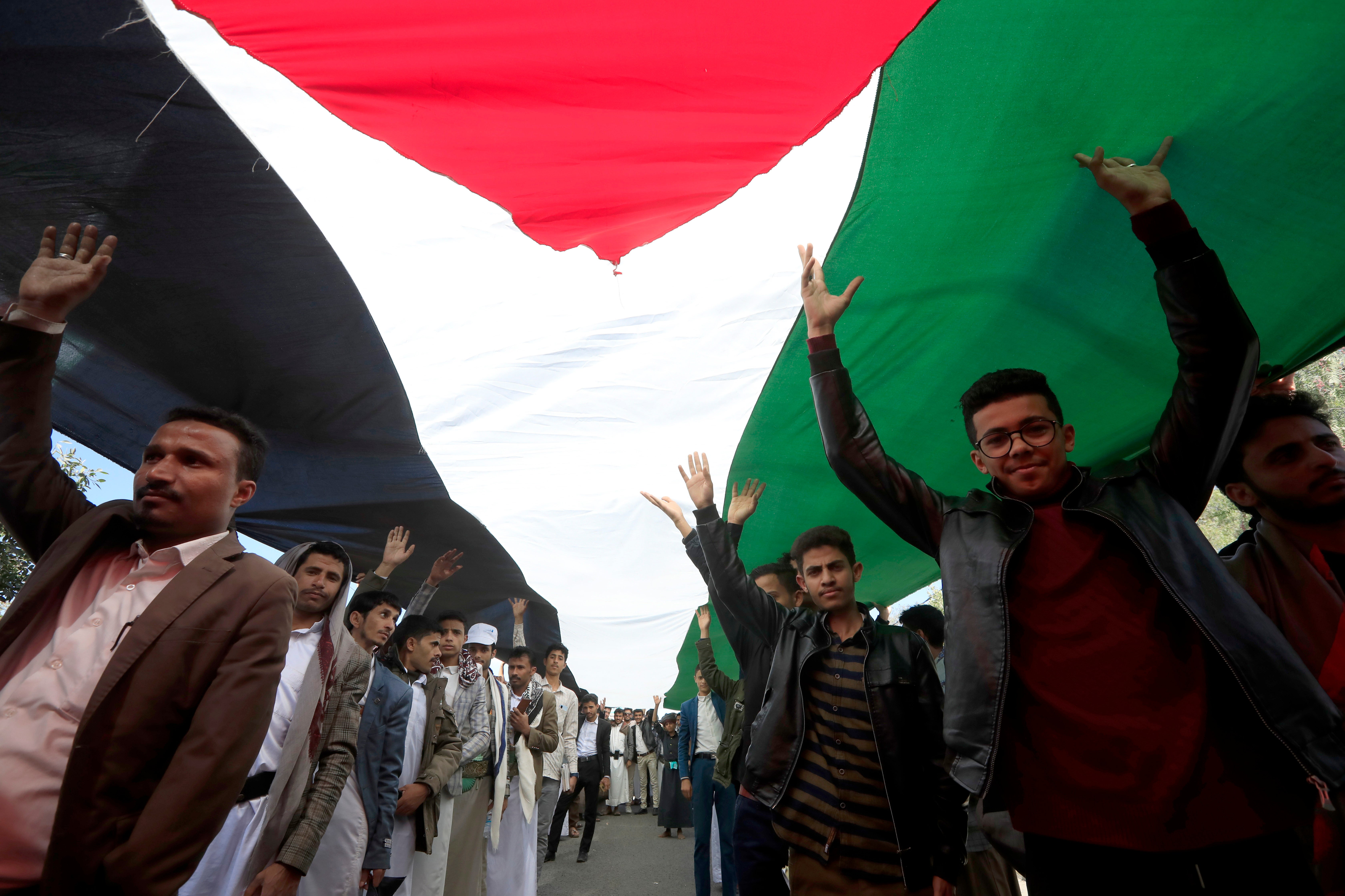 Students stand under a Palestinian flag during a rally in solidarity with the Palestinian people, at Sana’a University, in Sana’a, Yemen, on 14 February
