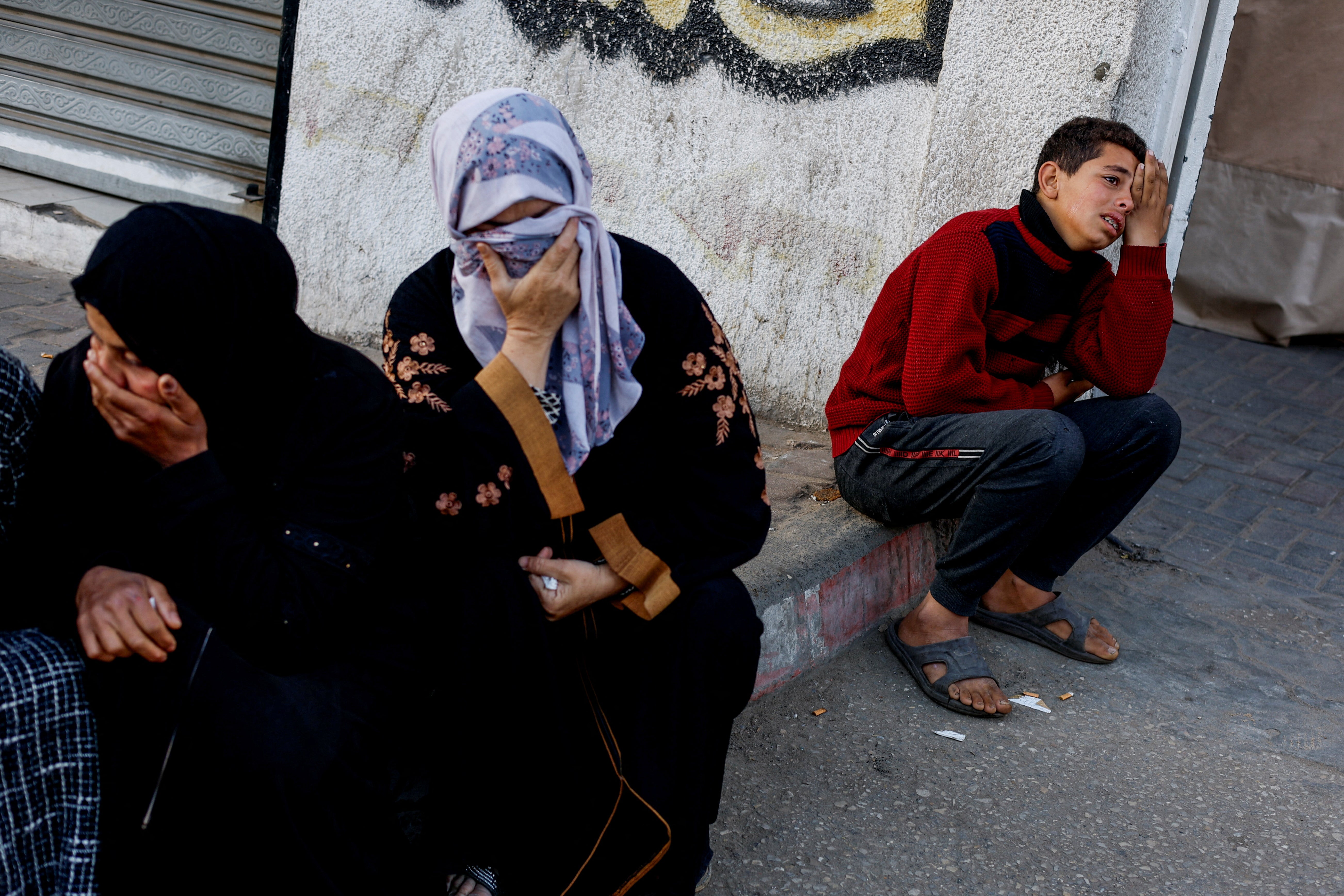 Mourners react as the bodies of Palestinians killed in Israeli strikes lie at Abu Yousef Al-Najjar hospital