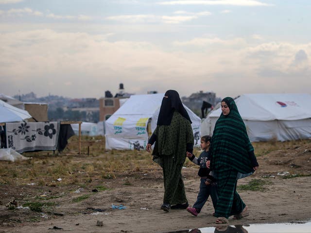 <p> Displaced Palestinian women from Rafah walk next to their shelters in Deir Al Balah, southern Gaza, in February 2024</p>