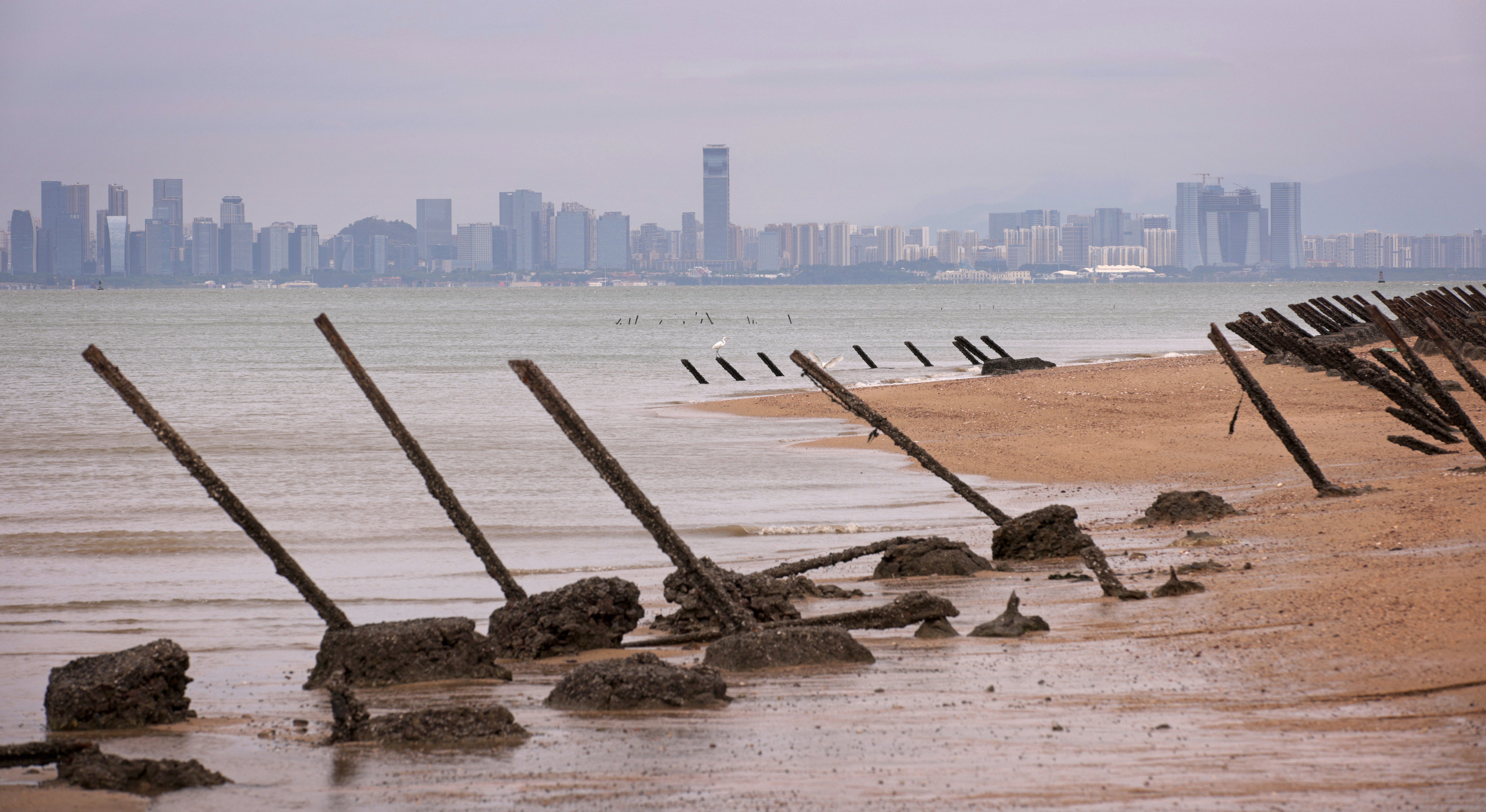 As the city of Xiamen, China, is seen in the background, wartime anti-tank obstacles sit on a beach on October 7, 2023 in Kinmen, Taiwan