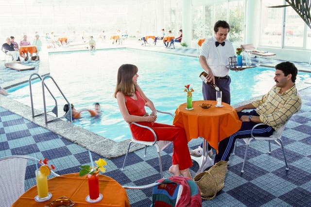 <p>A couple lounging poolside with brightly coloured cocktails </p>