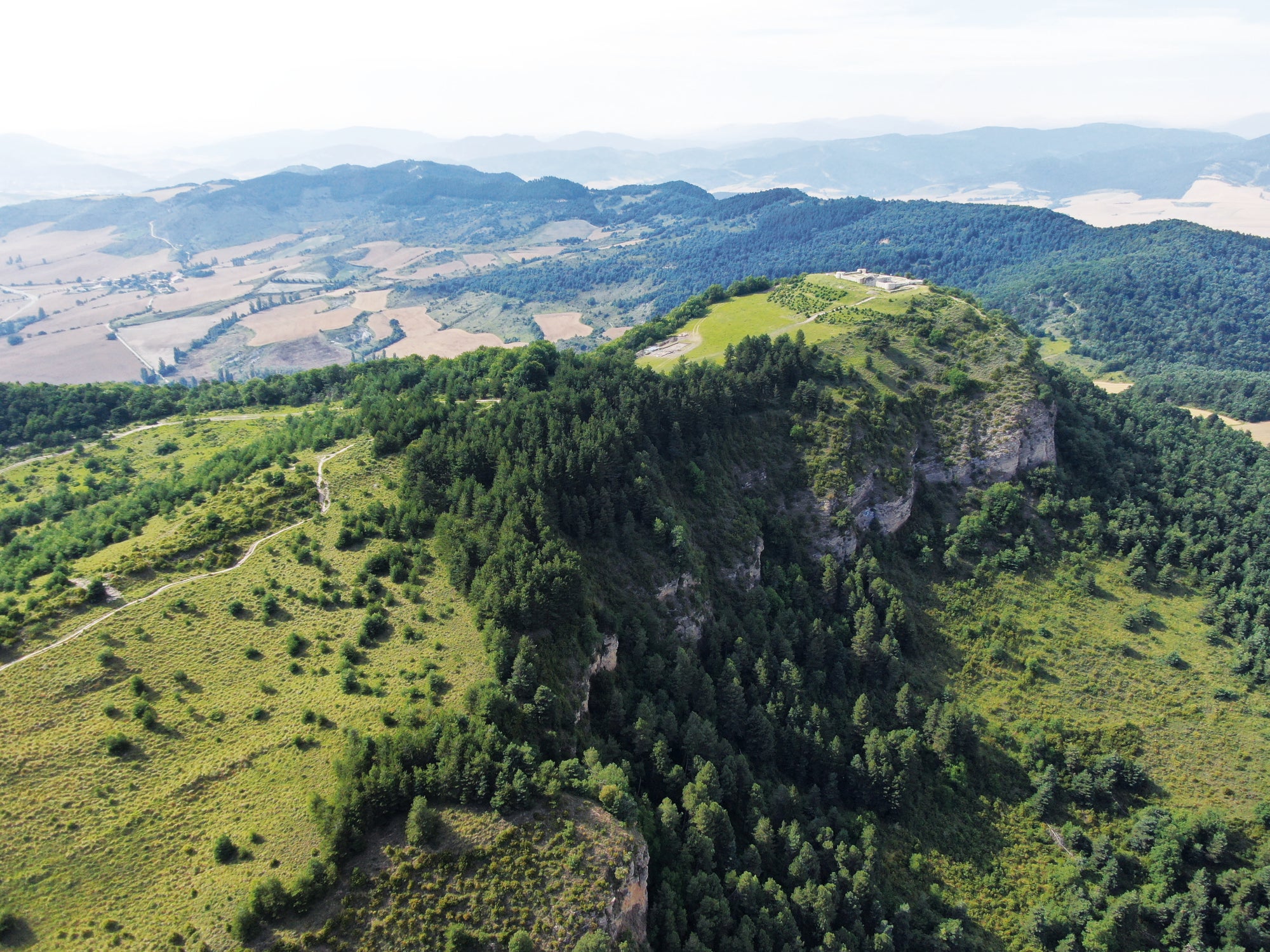 Dramatic photograph showing the mountaintop location of the ancient Basque fortified settlement - and the cliffs which surround it on three sides.