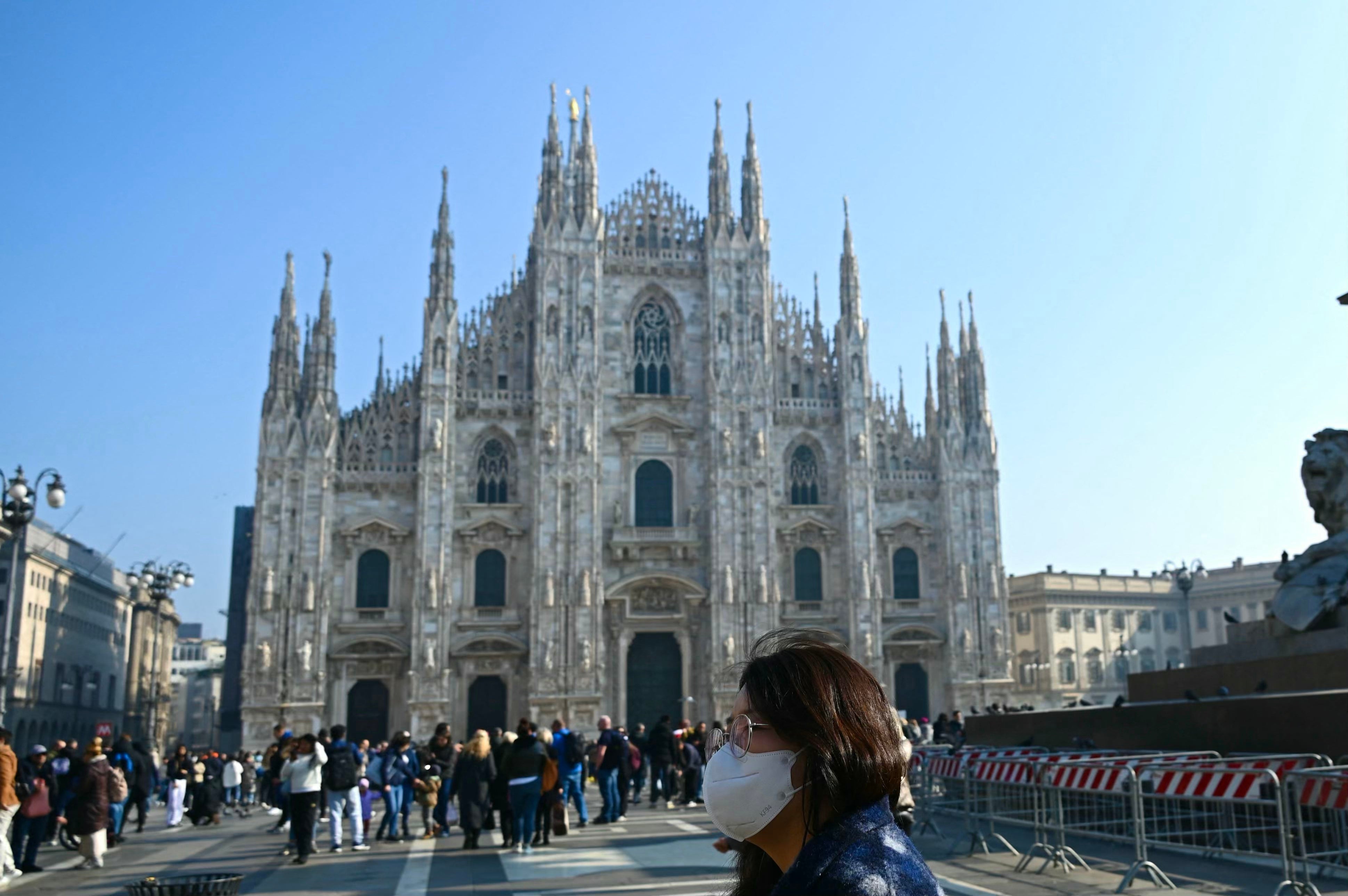 A woman wearing a mask walks at Piazza Duomo in Milan on Tuesday