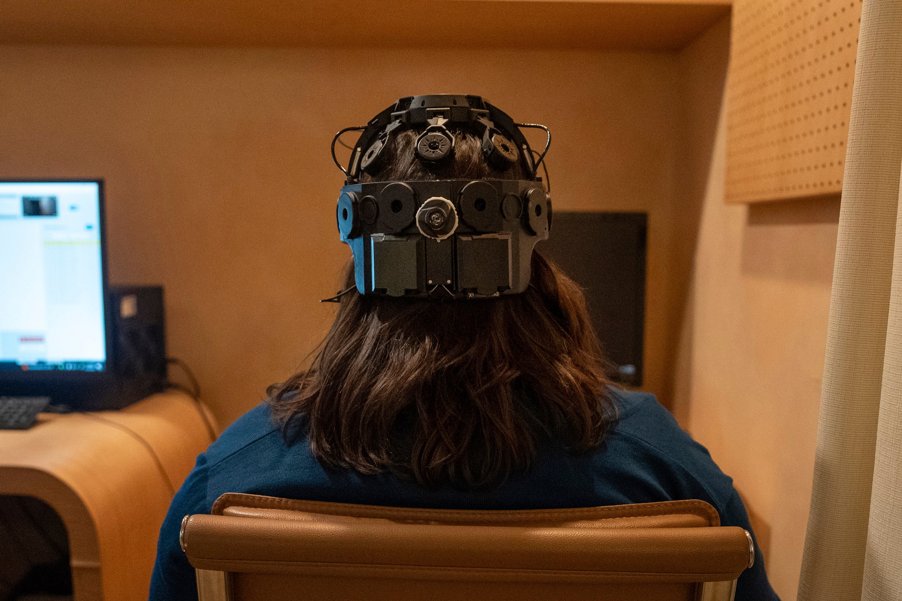 Emily Hollenbeck, a deep brain stimulation therapy patient, demonstrates an EEG device that records brain activity