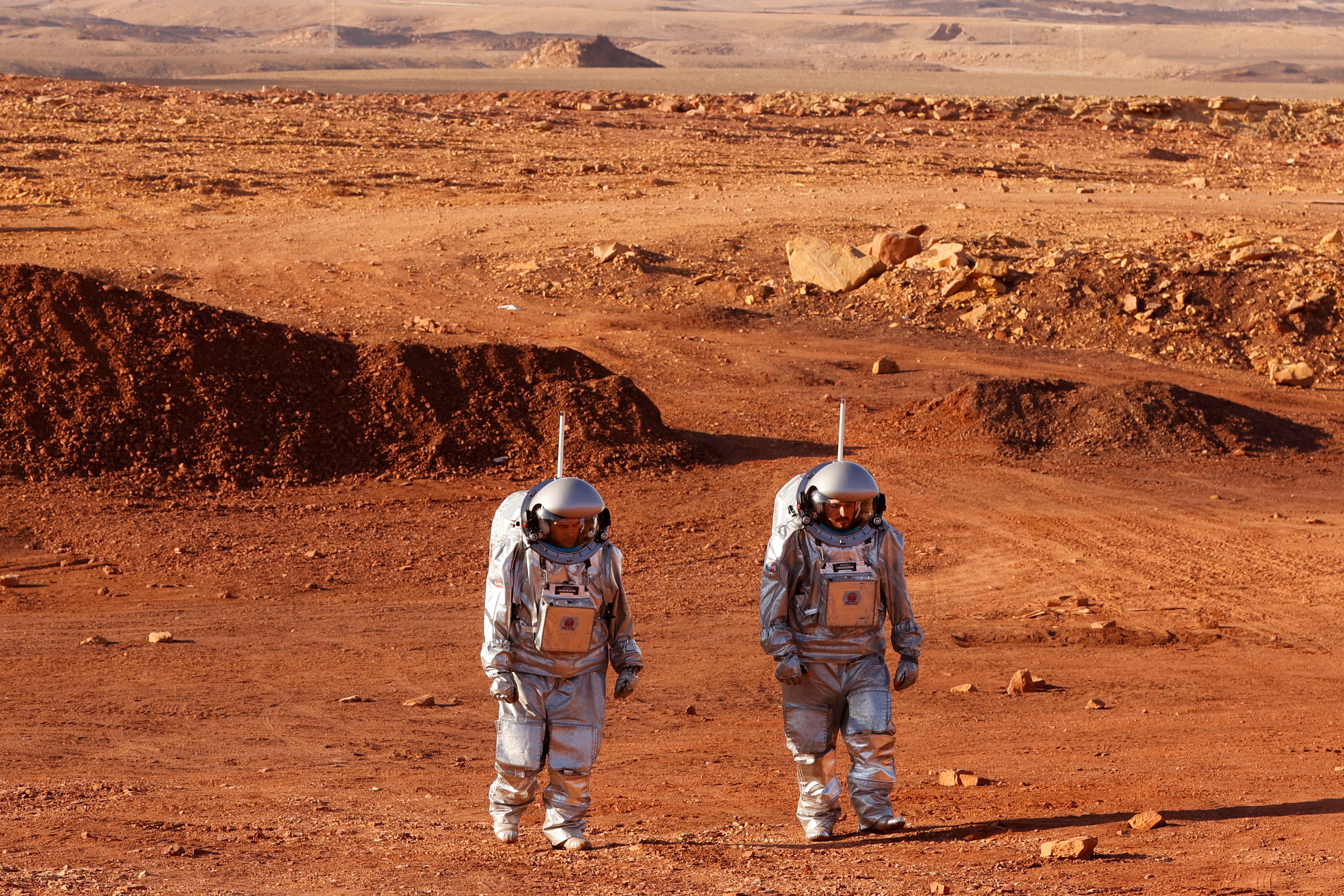 <p>A couple of astronauts from a team from Europe and Israel walk in spacesuits during a training mission for planet Mars at a site that simulates an off-site station at the Ramon Crater in Mitzpe Ramon in Israel’s southern Negev desert on October 10, 2021</p>