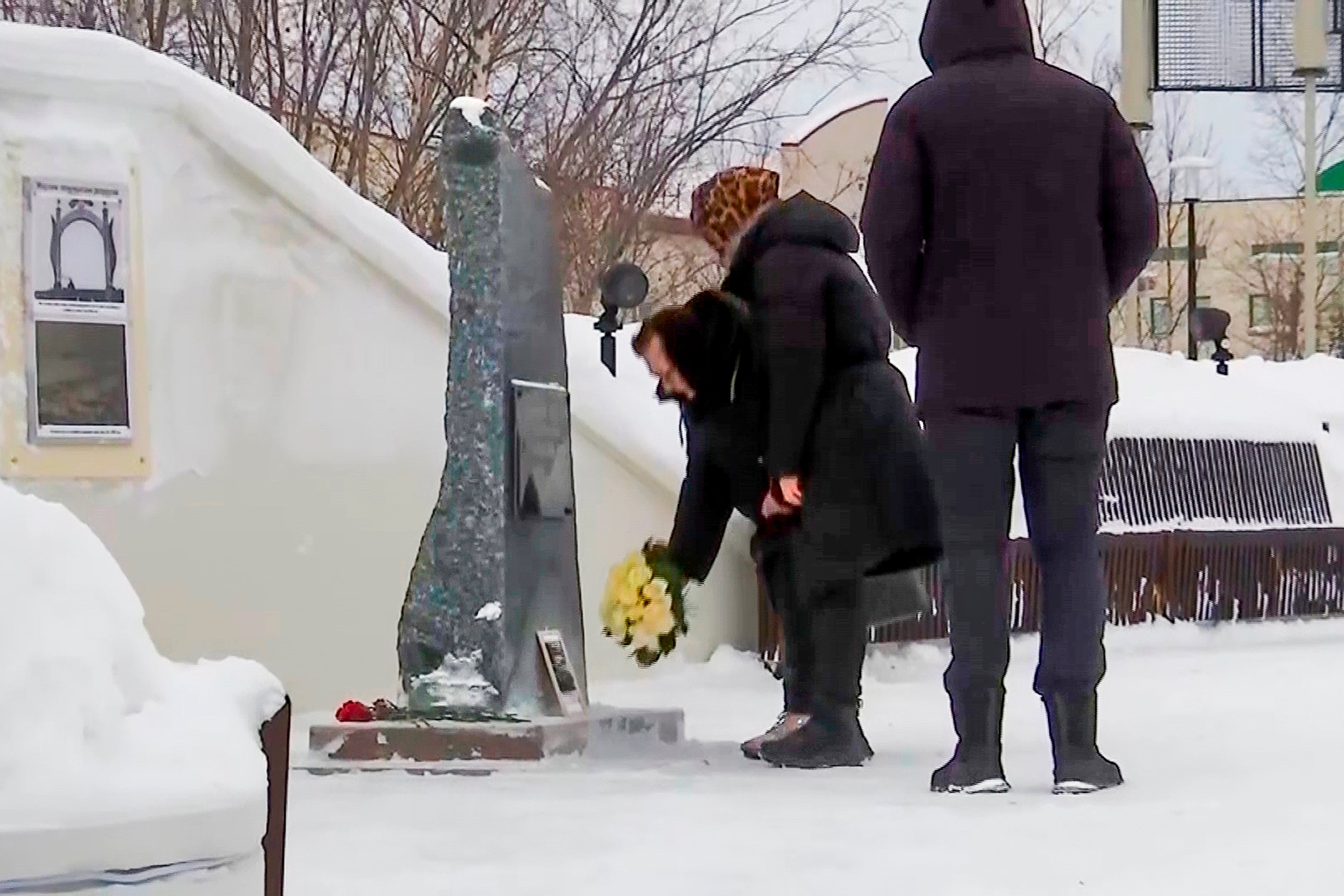 In this grab taken from video, Lyudmila Navalnaya, mother of Russian opposition leader Alexei Navalny, center, pay tribute to her son Alexei Navalny at the at the memorial to victims of political repression, in Salekhard