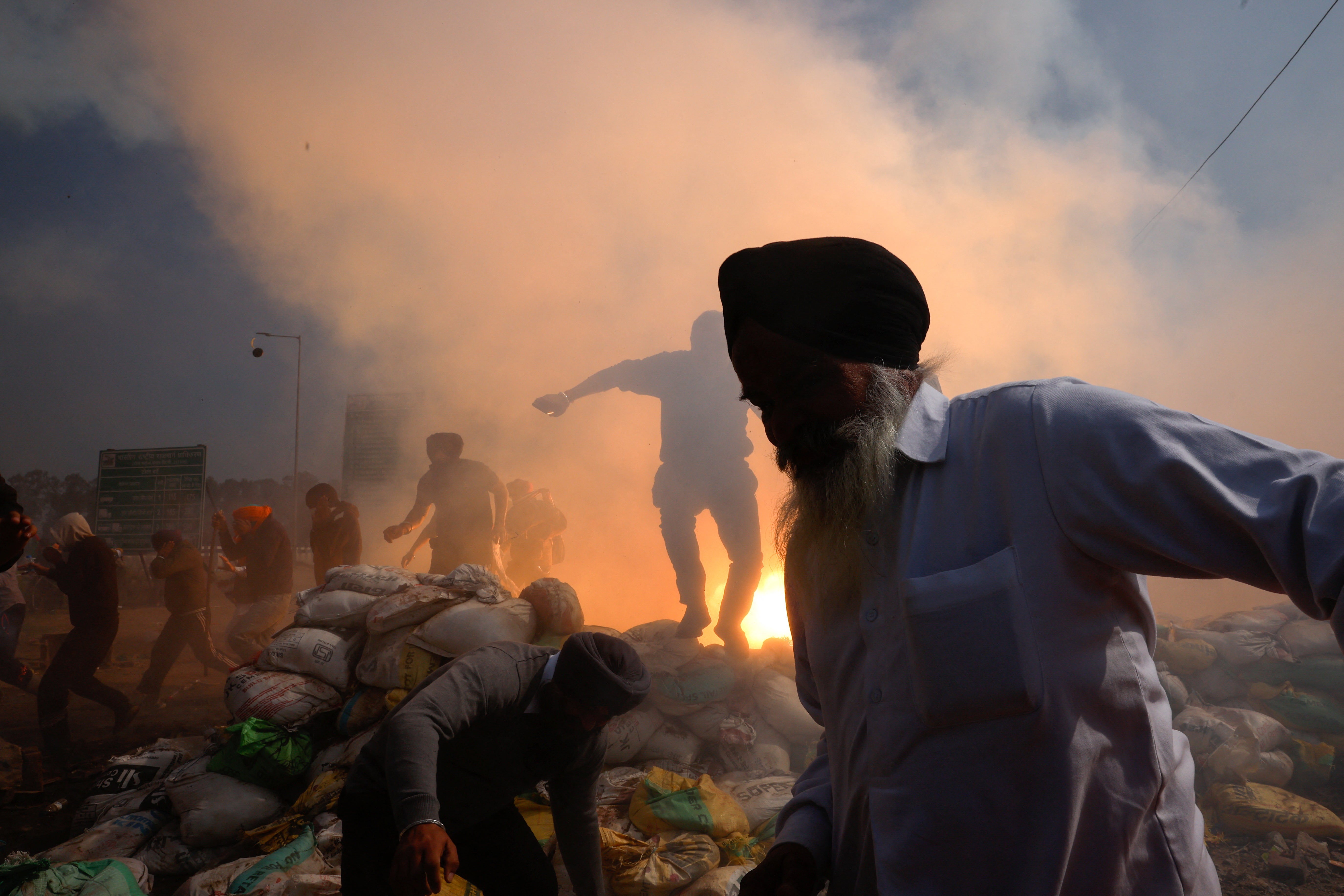 Farmers, who are marching towards New Delhi to press for better crop prices promised to them in 2021, run for cover amidst tear gas fired by police to disperse them at Shambhu barrier, a border crossing between Punjab and Haryana states, India, 21 February 2024