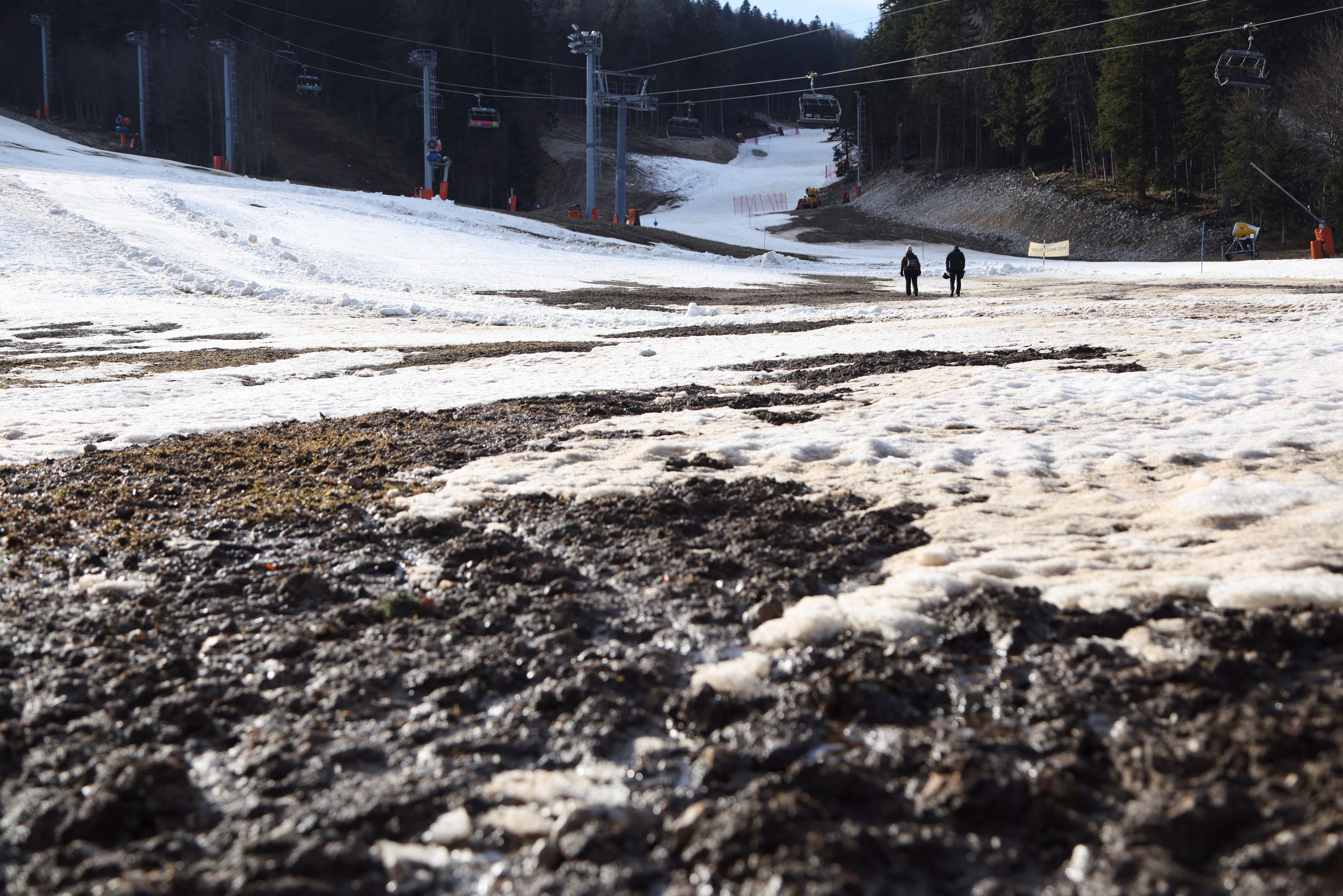 Visitors walk on the remaining traces of snow mixed with mud during Bosnia's unseasonably warm weather on Mount Bjelasnica