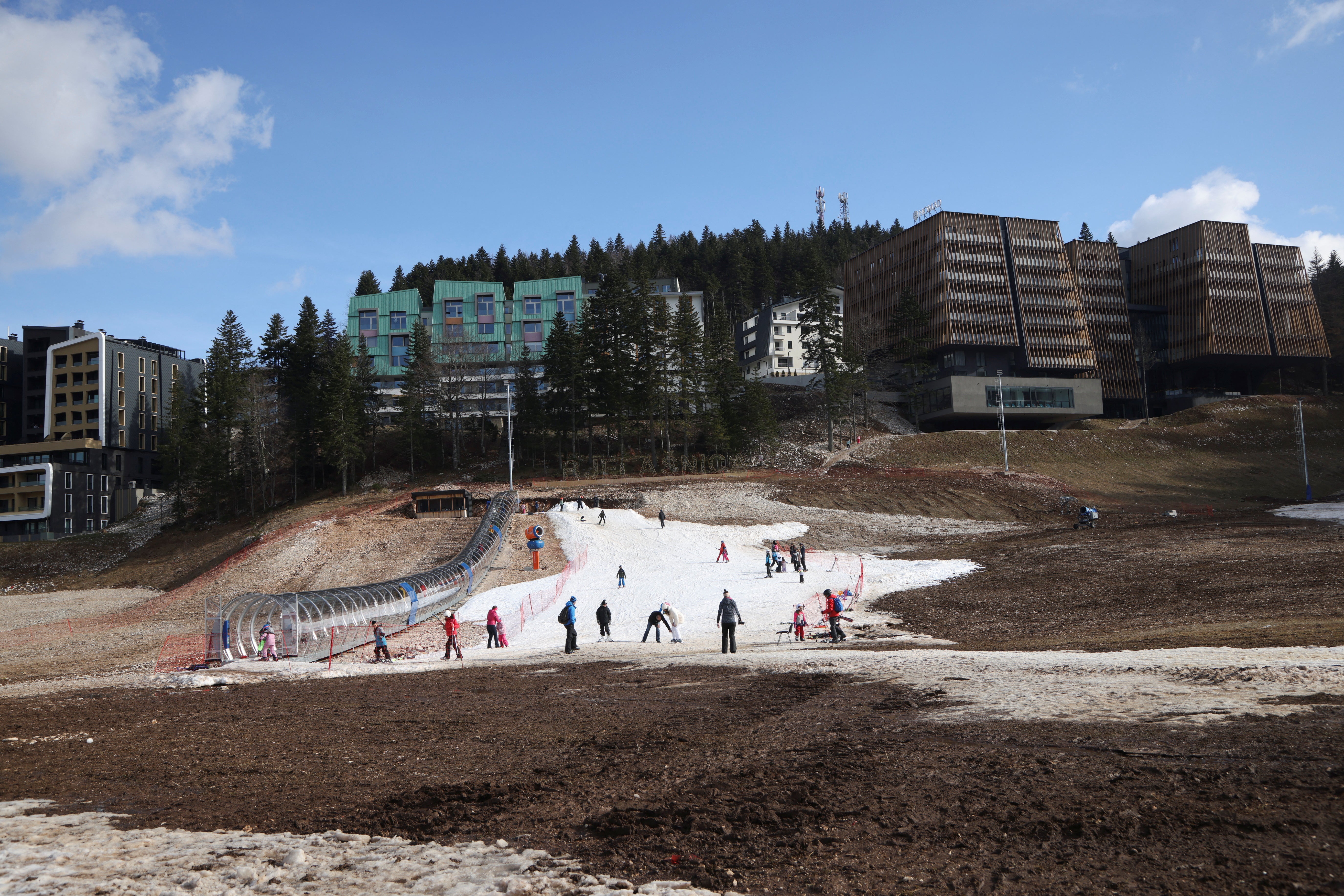 Visitors walk on the remaining traces of snow mixed with mud during Bosnia's unseasonably warm weather on Mount Bjelasnica