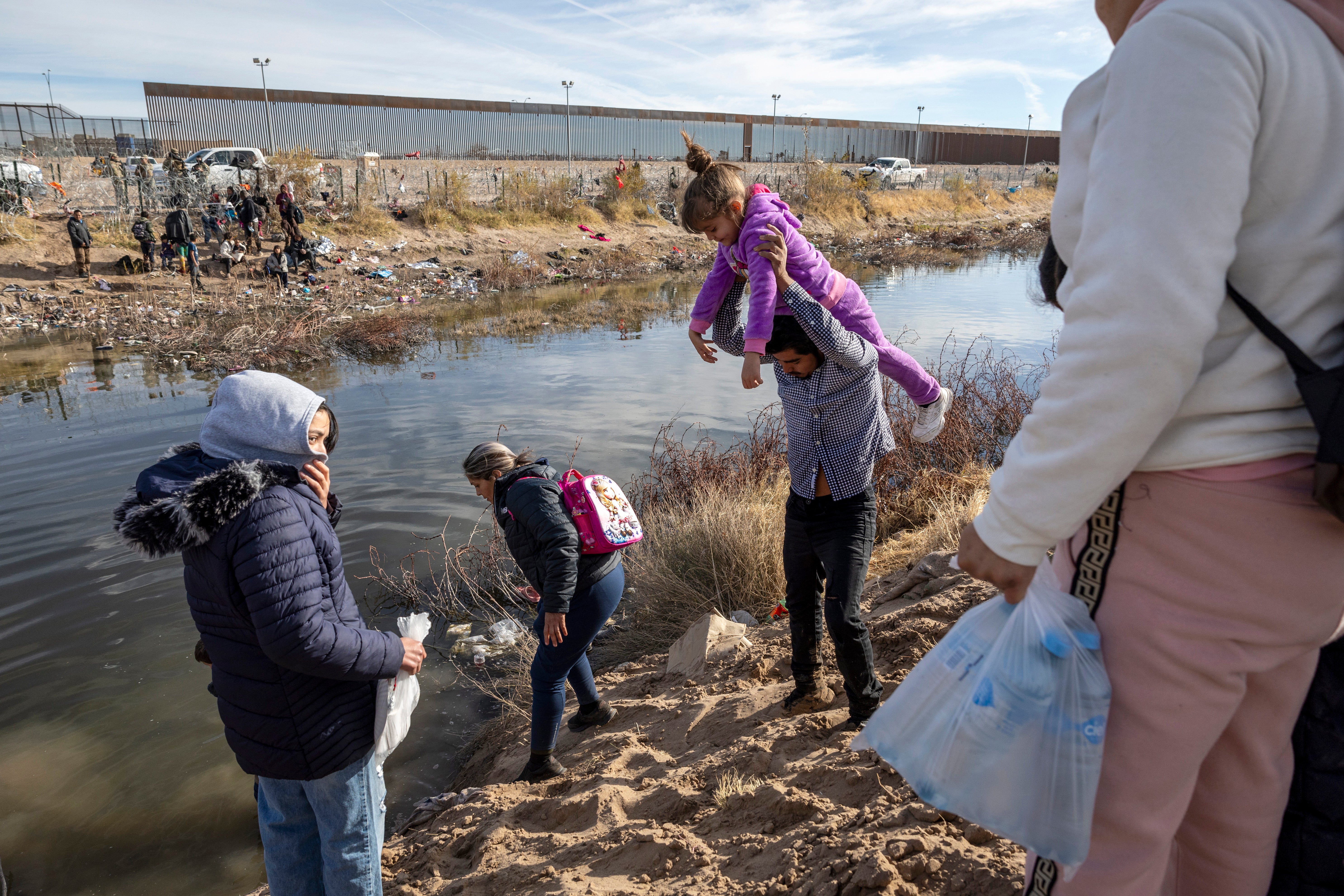 Immigrant families prepare to wade across the Rio Grande into El Paso, Texas on 30 January 2024 from Ciudad Juarez, Mexico