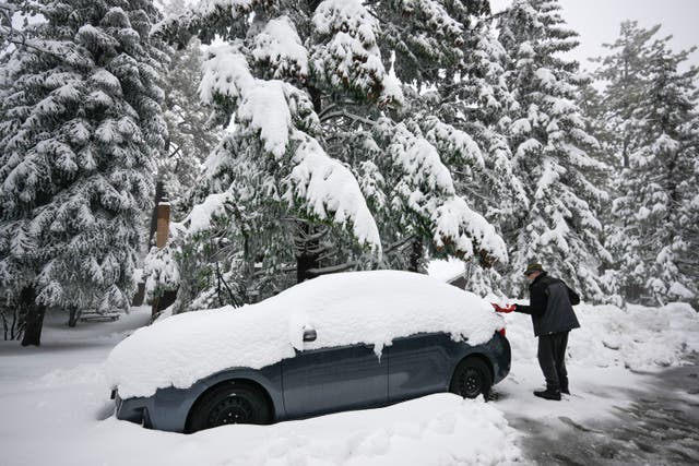 <p>A man shovels snow off his car after heavy snow hit California earlier this month </p>