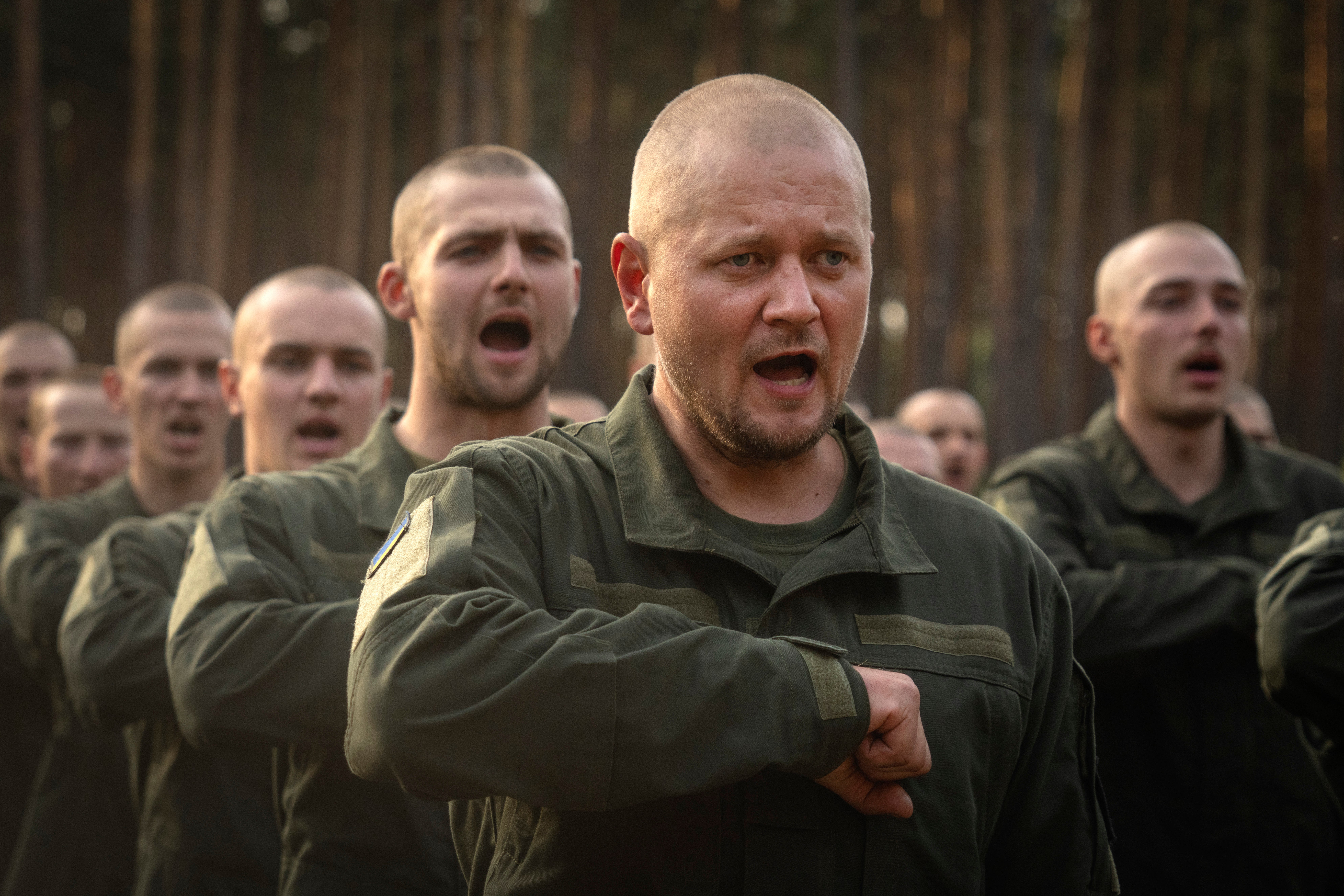 Newly recruited soldiers toss their hats as they celebrate the end of their training at a military base close to Kyiv