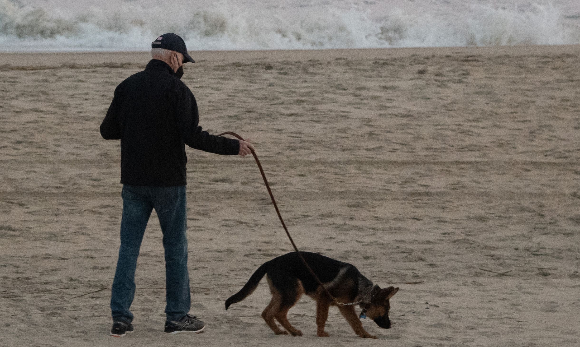 President Joe Biden walks his dog Commander on the beach in Rehoboth Beach, Delaware, December 28, 2021. A new report says the president saw his dog attack Secret Service Agents.