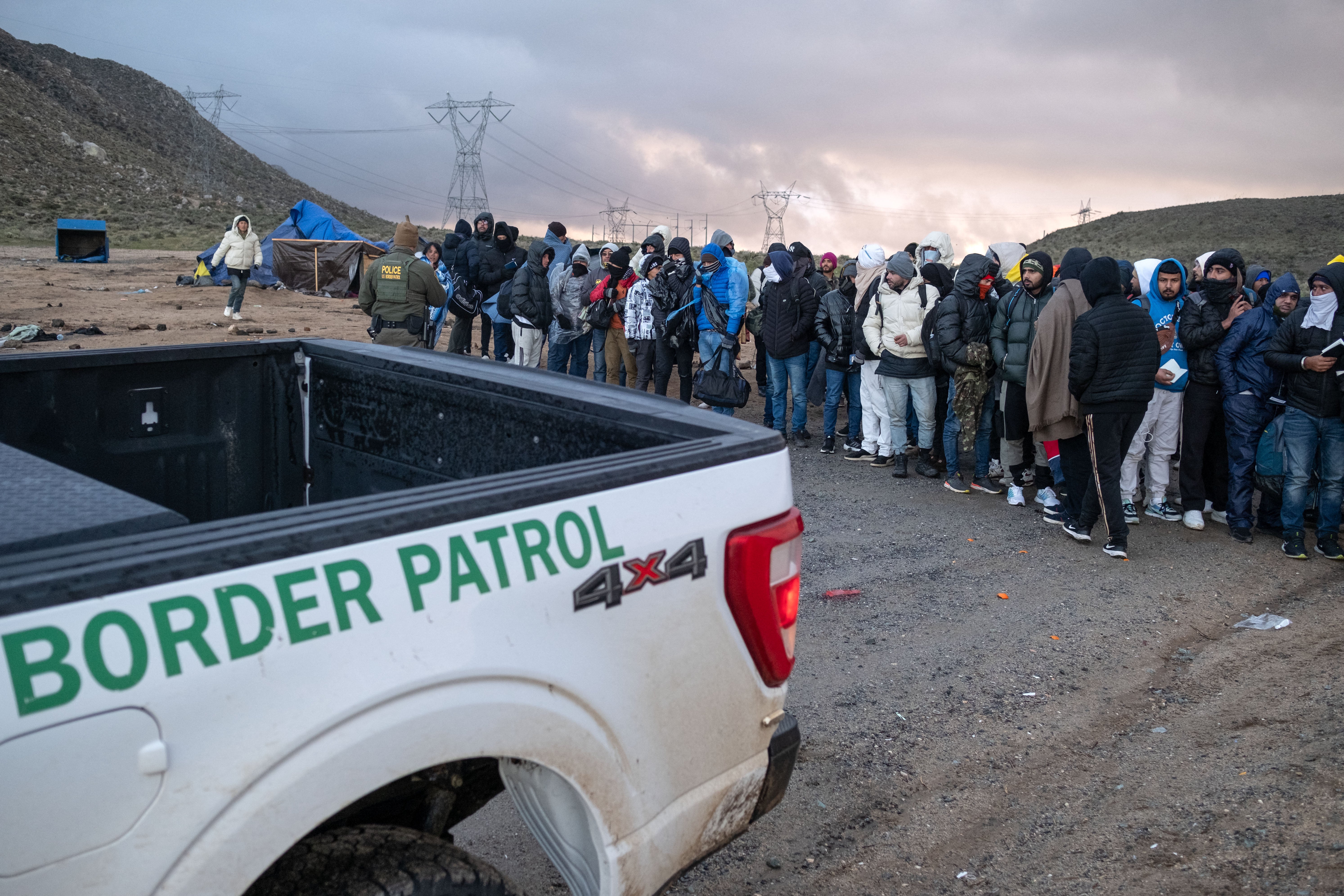 People seeking asylum wait in line to be processed by border patrol agents near the US-Mexico border outside California on 2 January