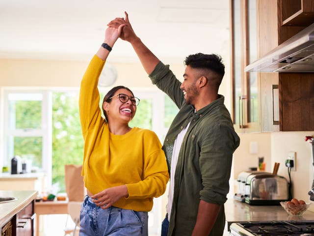 <p>A couple dances together in their kitchen. </p>