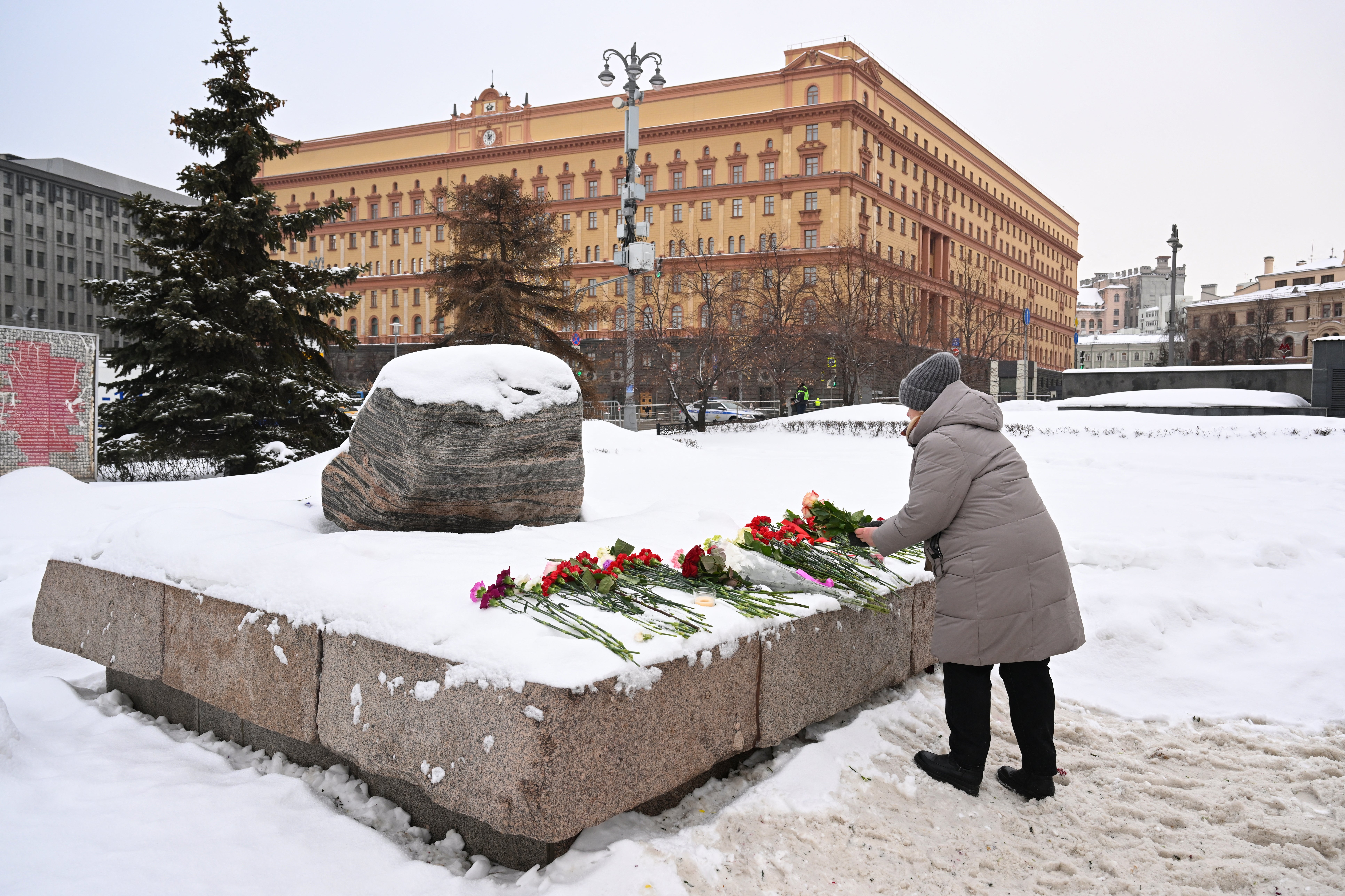 A woman lays flowers for Navalny at the Solovetsky Stone, a monument to political repression and one of the locations where tributes have been left by Russians for the late opposition leader