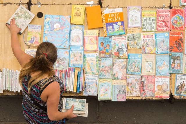 <p>A bookseller laying out her books at the Southbank Centre book market in London.</p>