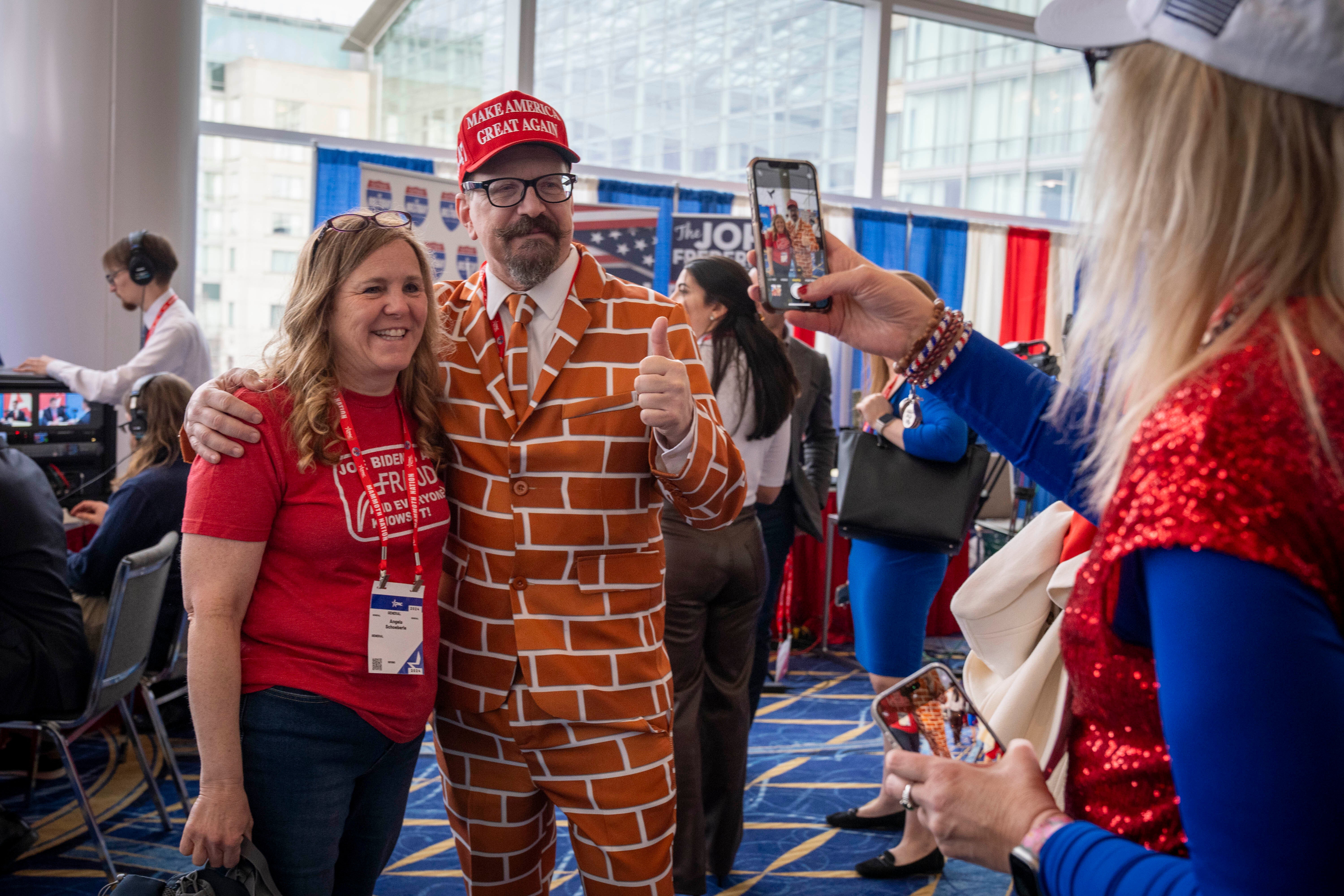 Blake Marnell, of San Diego, center, dressed in his “wall suit,” poses for a photo with other another attendee of the Conservative Political Action Conference, CPAC 2024, at National Harbor in Oxon Hill, MD