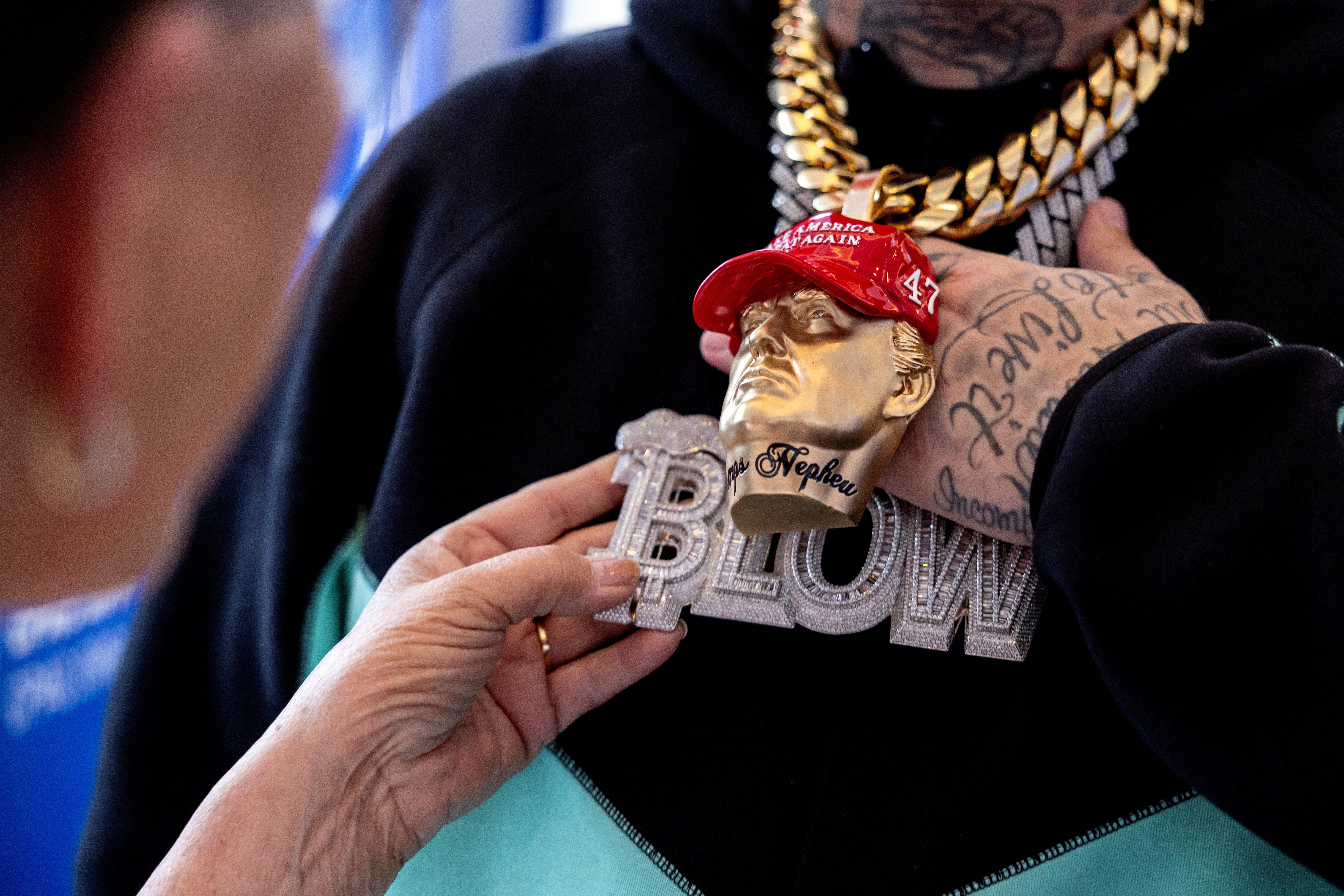 Rapper Forgiato Blow shows a person his Trump-themed jewelry at the Conservative Political Action Conference (CPAC) annual meeting in National Harbor, Maryland, U.S., February 22, 2024