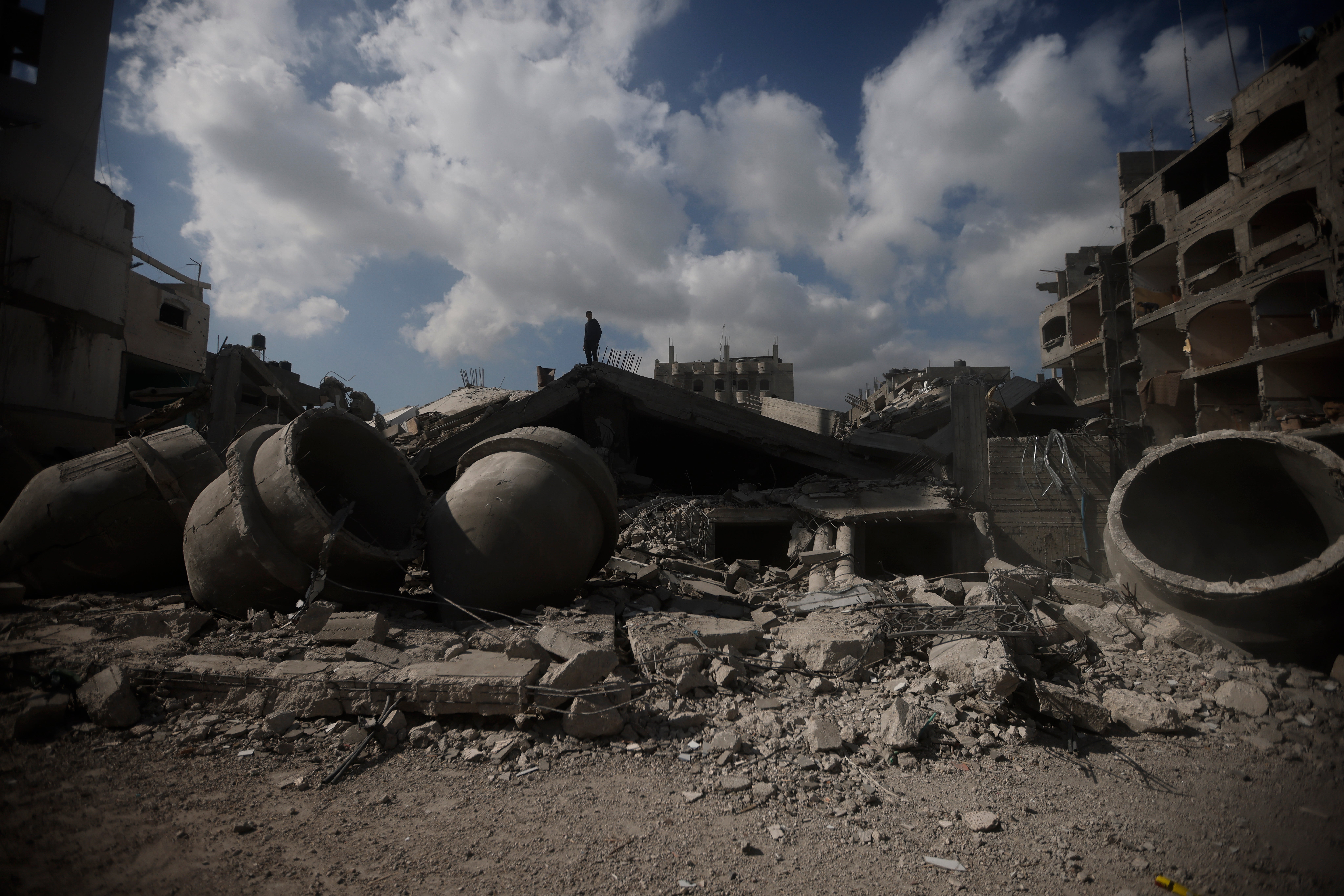 <p>A Palestinian man stands on top of a destroyed mosque </p>