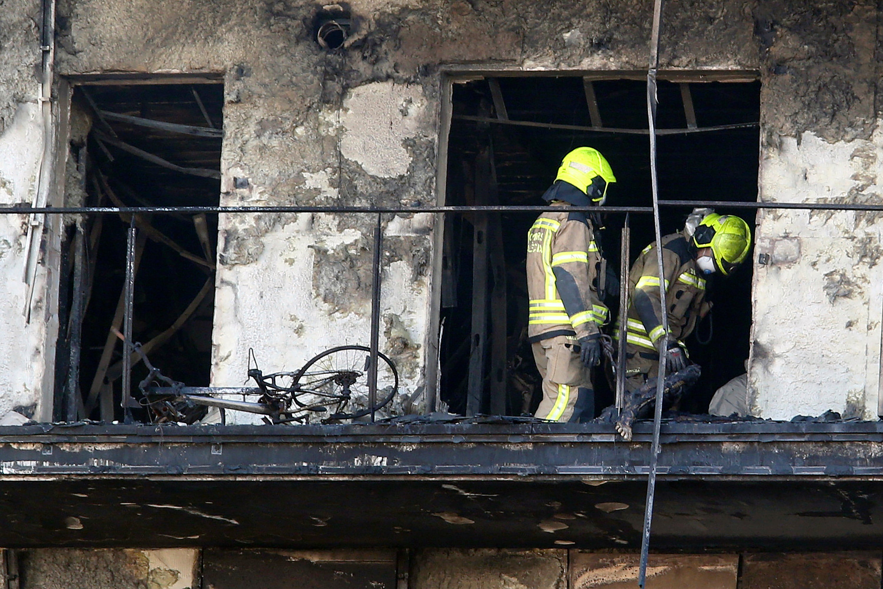 Firefighters remove a charred body inside a burned block building in Valencia, Spain, Friday, Feb. 23, 2024