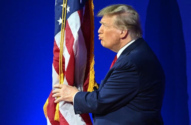 <p>Former US President and 2024 presidential hopeful Donald Trump kisses the US flag as he arrives to speak during the annual Conservative Political Action Conference (CPAC) meeting on February 24, 2024, in National Harbor, Maryland</p>