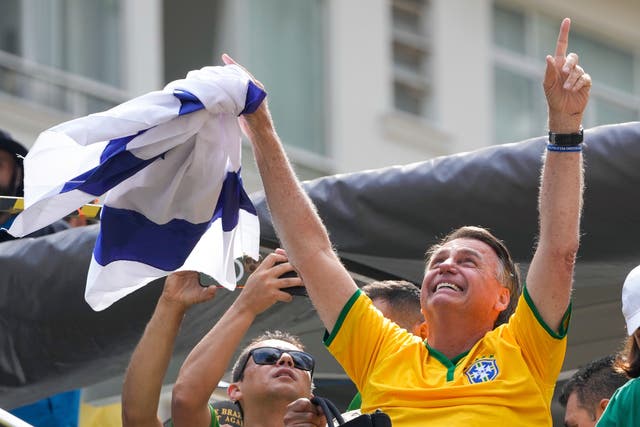 <p>Jair Bolsonaro waves an Israeli flag during a rally on Sunday </p>