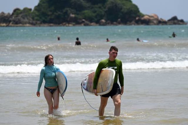 <p>File Tourists carry their surfing boards along a beach in picture taken on 26 March 2022</p>