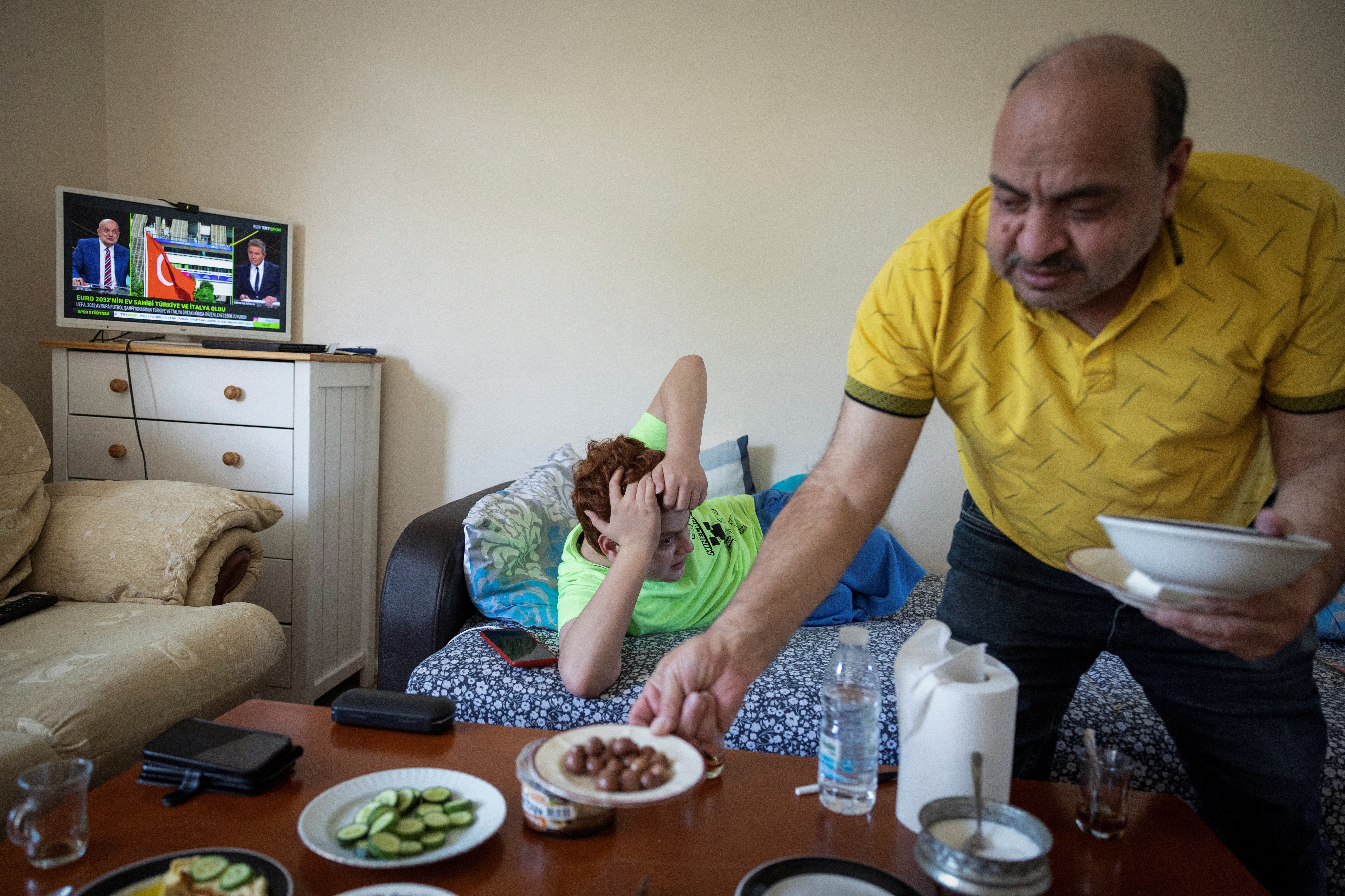 Hasan, prepares dinner for his son Mehmet, at his flat in London