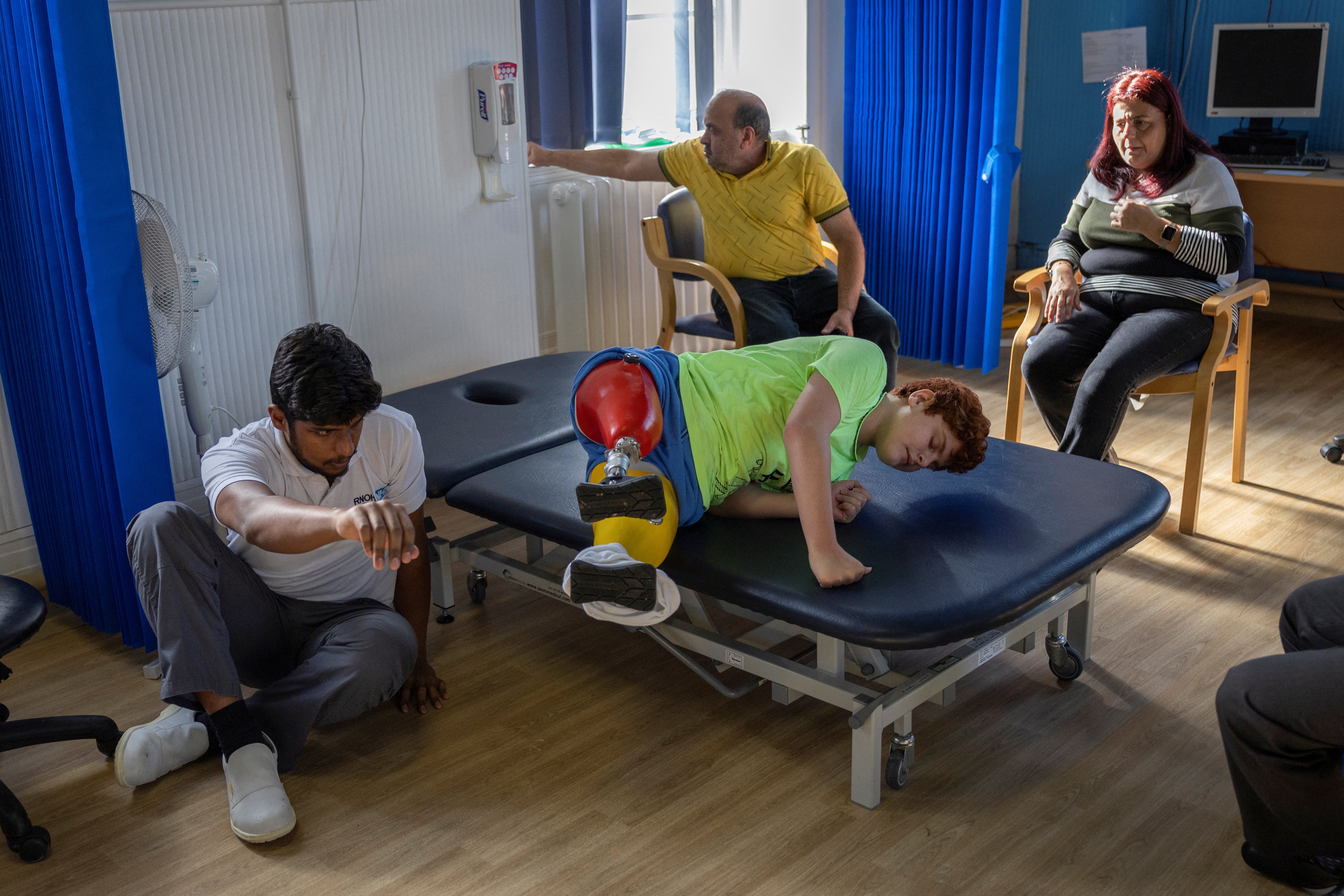 Prosthetist Paul Gandrapu attends to Mehmet Koc, 13, on a treatment bed at the Royal National Orthopaedic Hospital in London