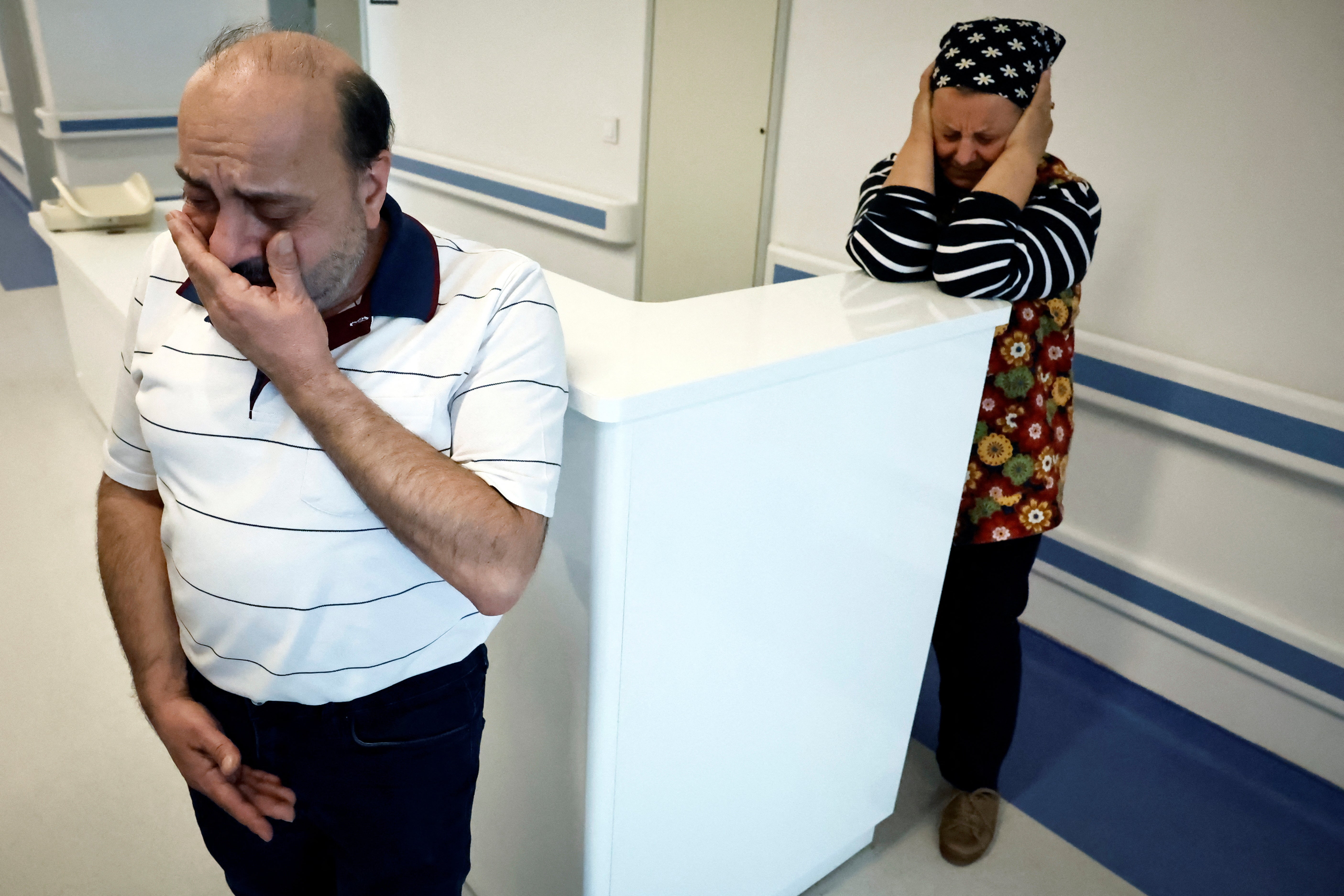 Hasan Koc and his late wife's mother Emine Karalioglu, 63, react in the hallway of Mersin hospital while his son Mehmet, screams as nurses change the bandages on his amputated legs in Turkey