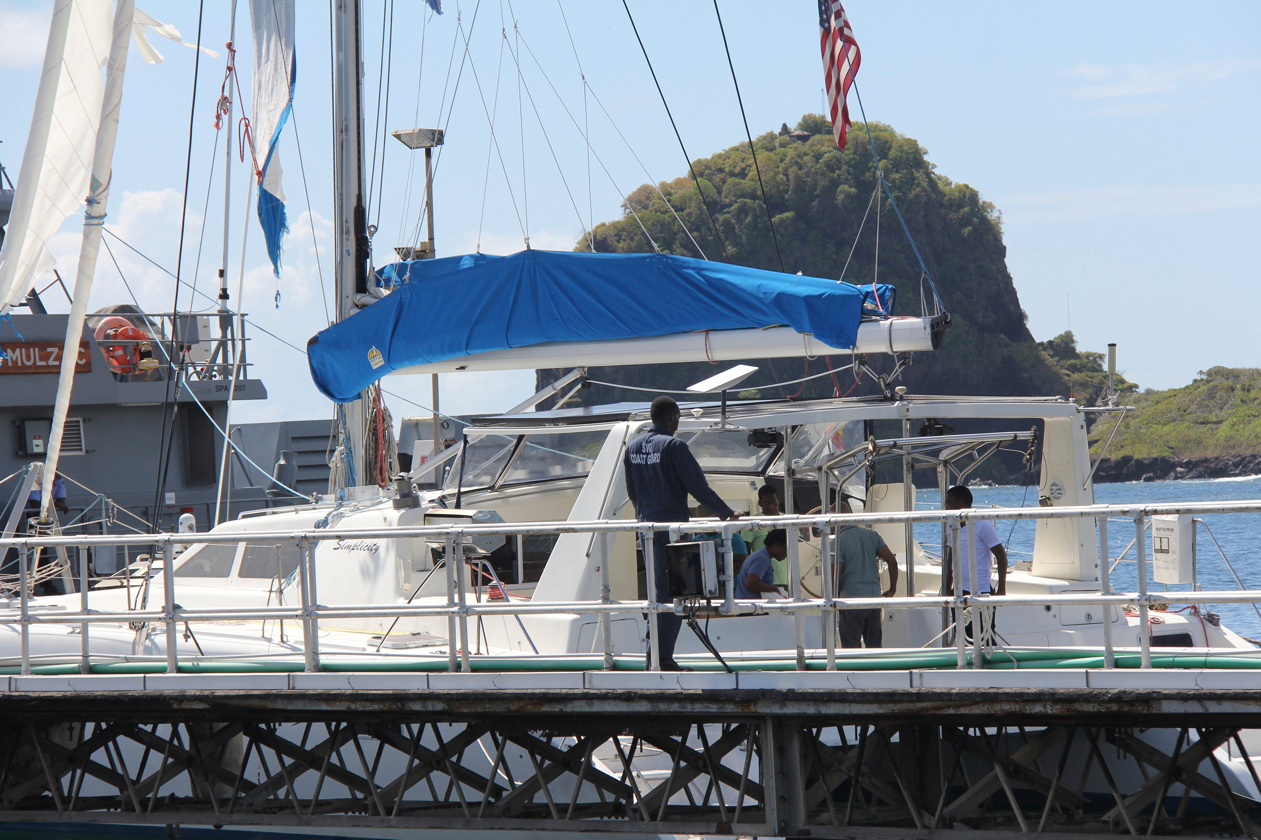 Investigators from Grenada and St. Vincent and the Grenadines stand aboard the yacht ‘Simplicity’