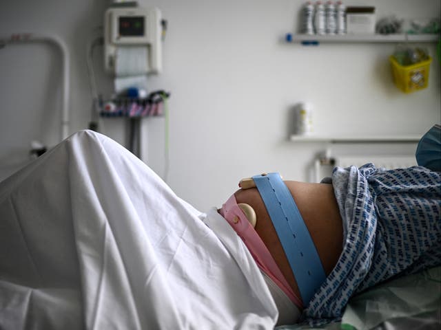<p>A pregnant woman lies on her bed with monitoring devices placed on her belly as she gets ready before delivering her child at the maternity ward of a hospital in Paris on June 29, 2022</p>