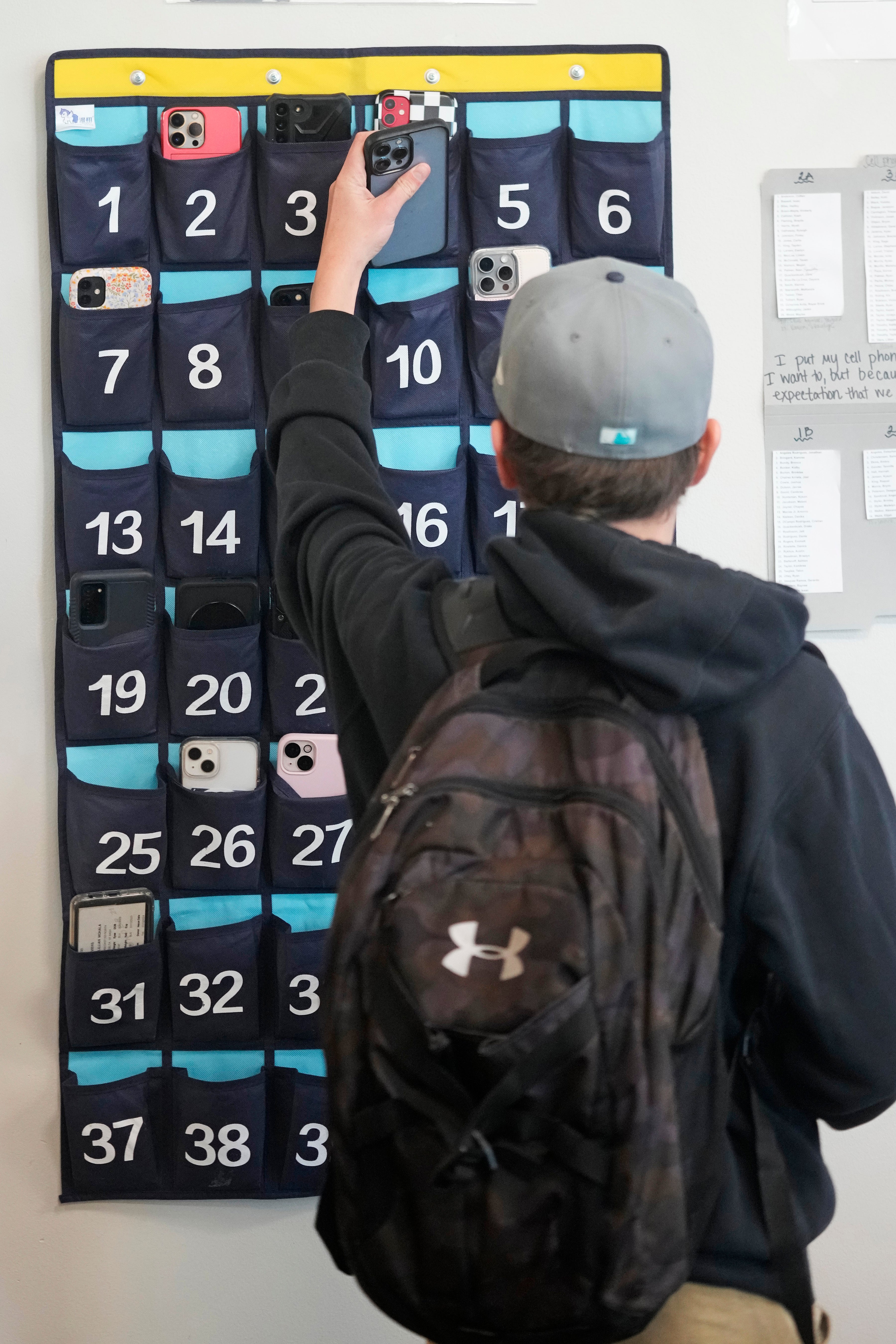 A student puts their ce,, phone into a holder amid a ban at school.